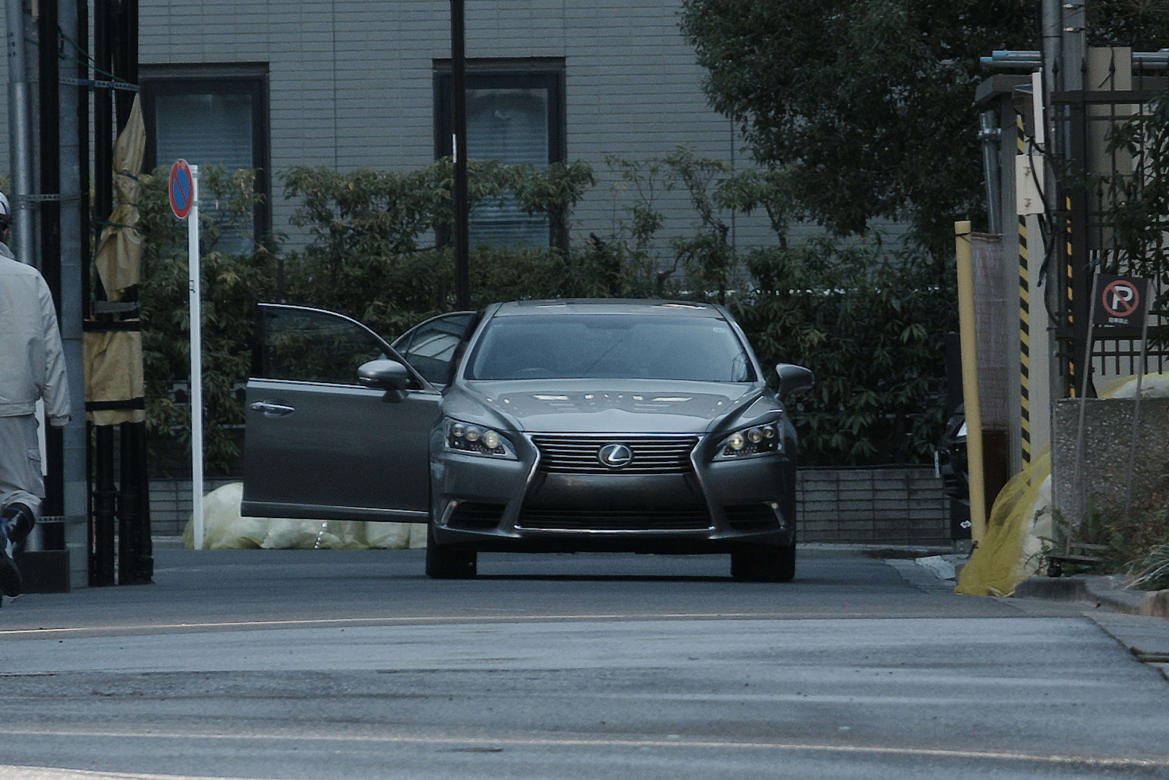 Gray luxury car with an open door driving down the street