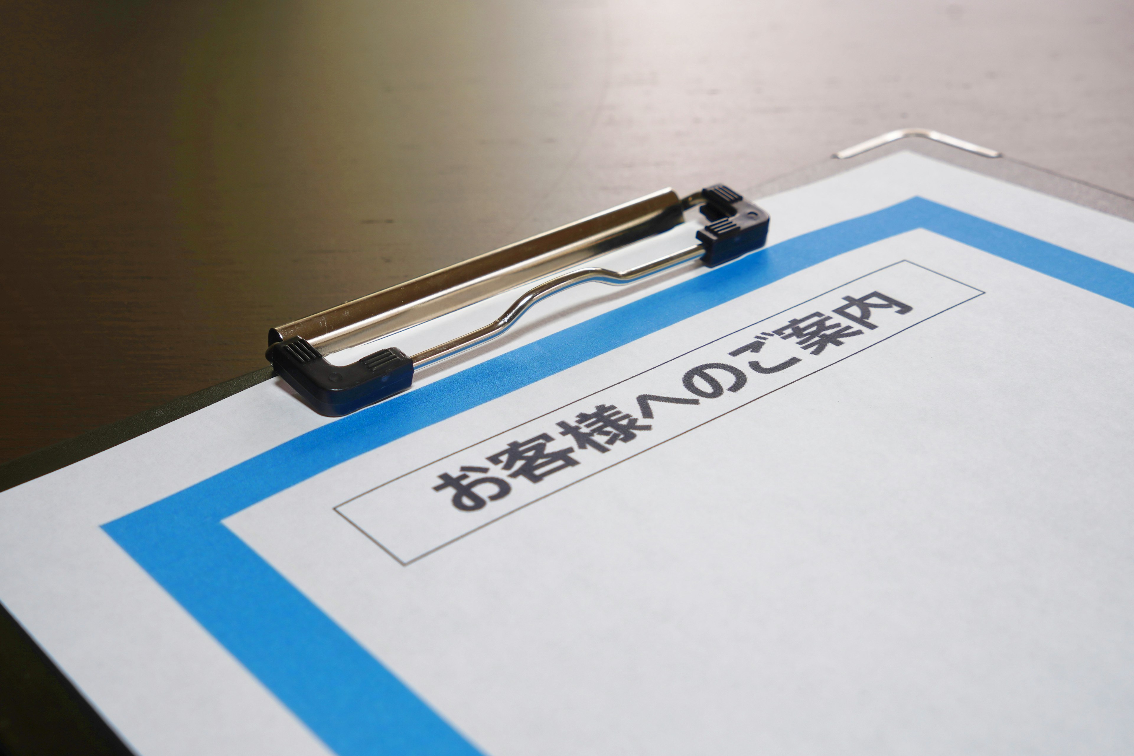 Clipboard with a white sheet bordered in blue featuring Japanese text for guidance