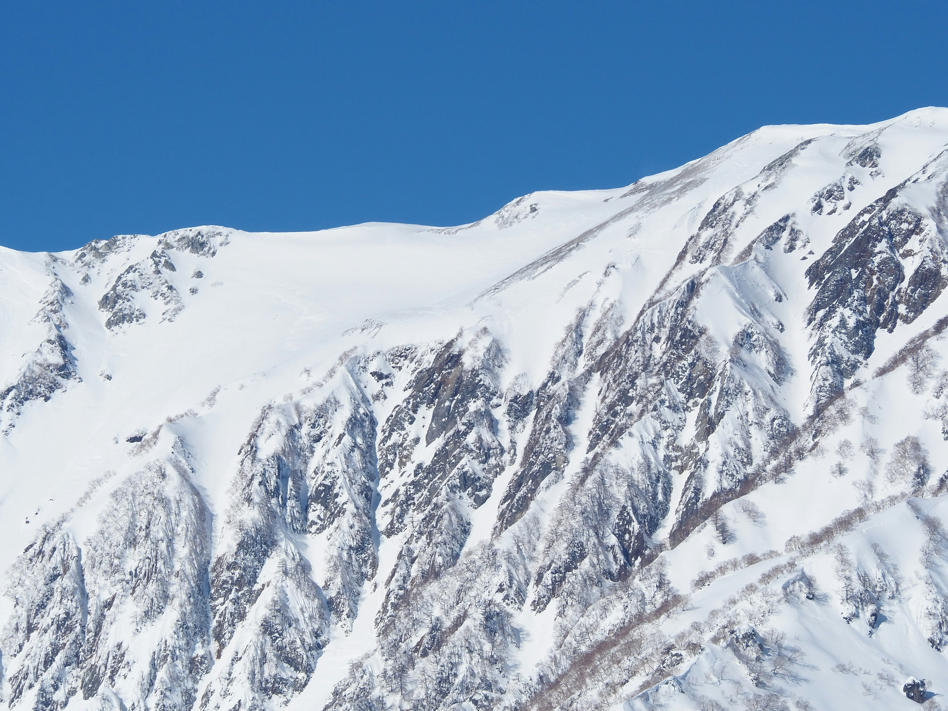 Schneebedeckte Berggipfel vor klarem blauen Himmel