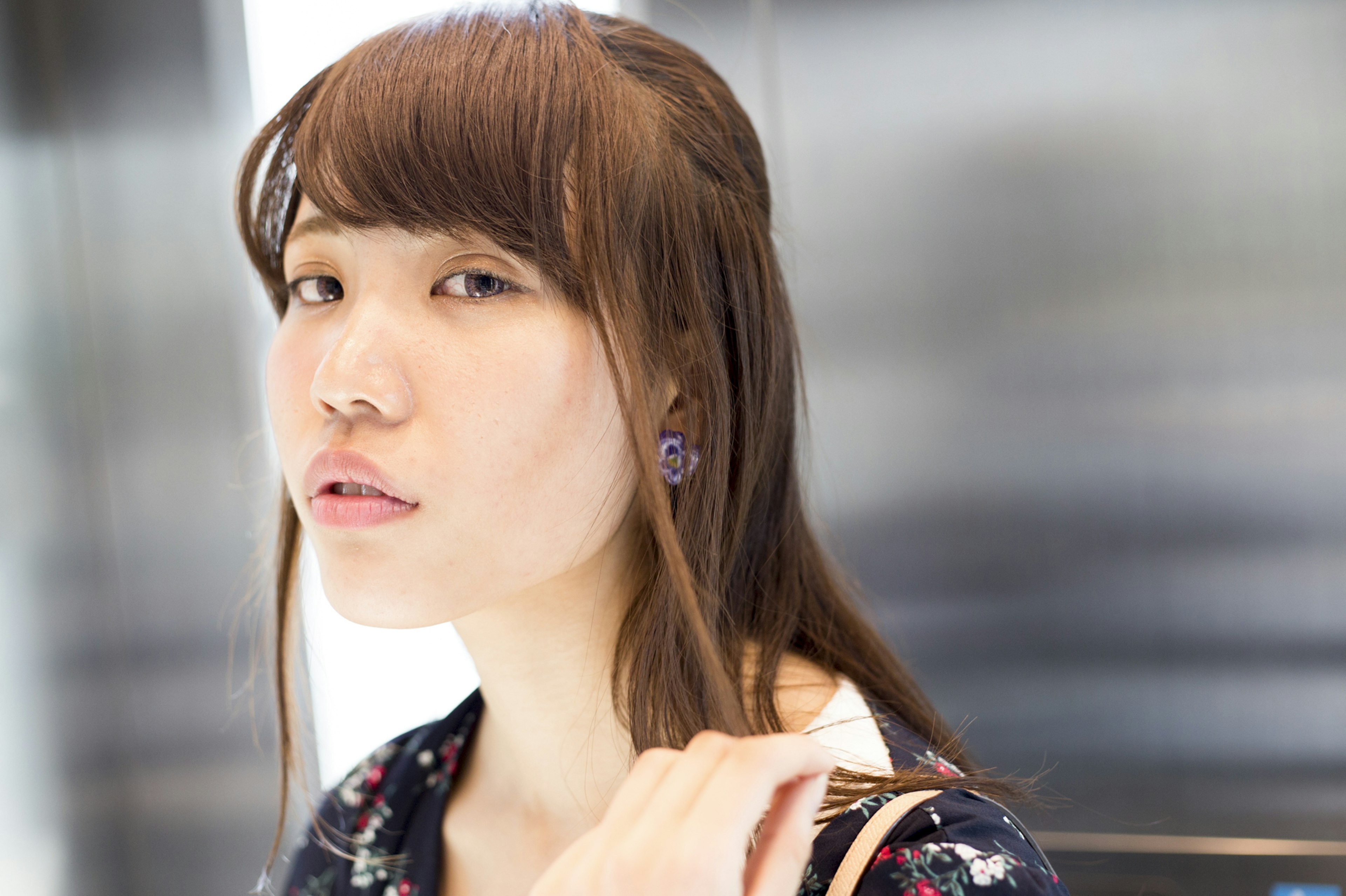 A woman looking at the camera with a slight smile Brown hair cascading over her shoulders Wearing a floral patterned outfit