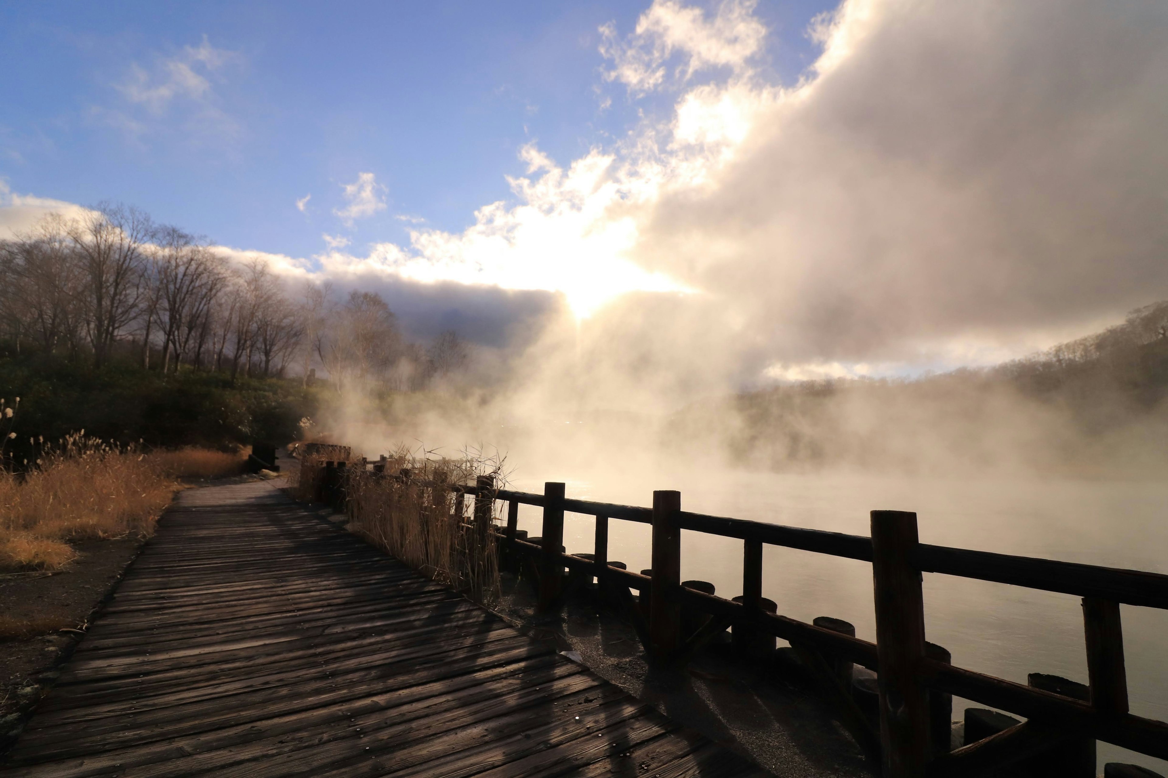 Vista panoramica di un lago nebbioso con un sentiero in legno