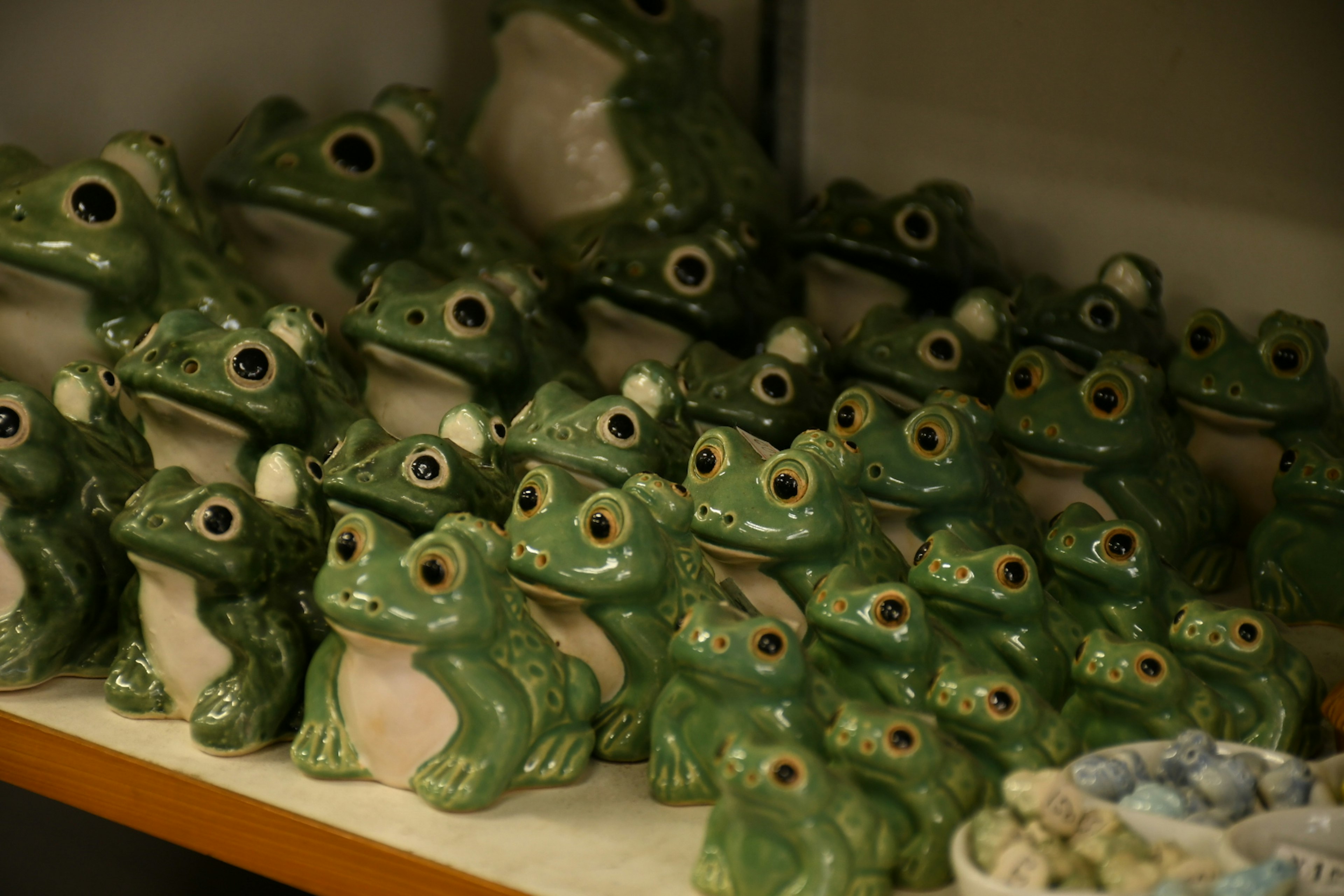 Una colección de figuritas de ranas de cerámica verde exhibidas en una estantería