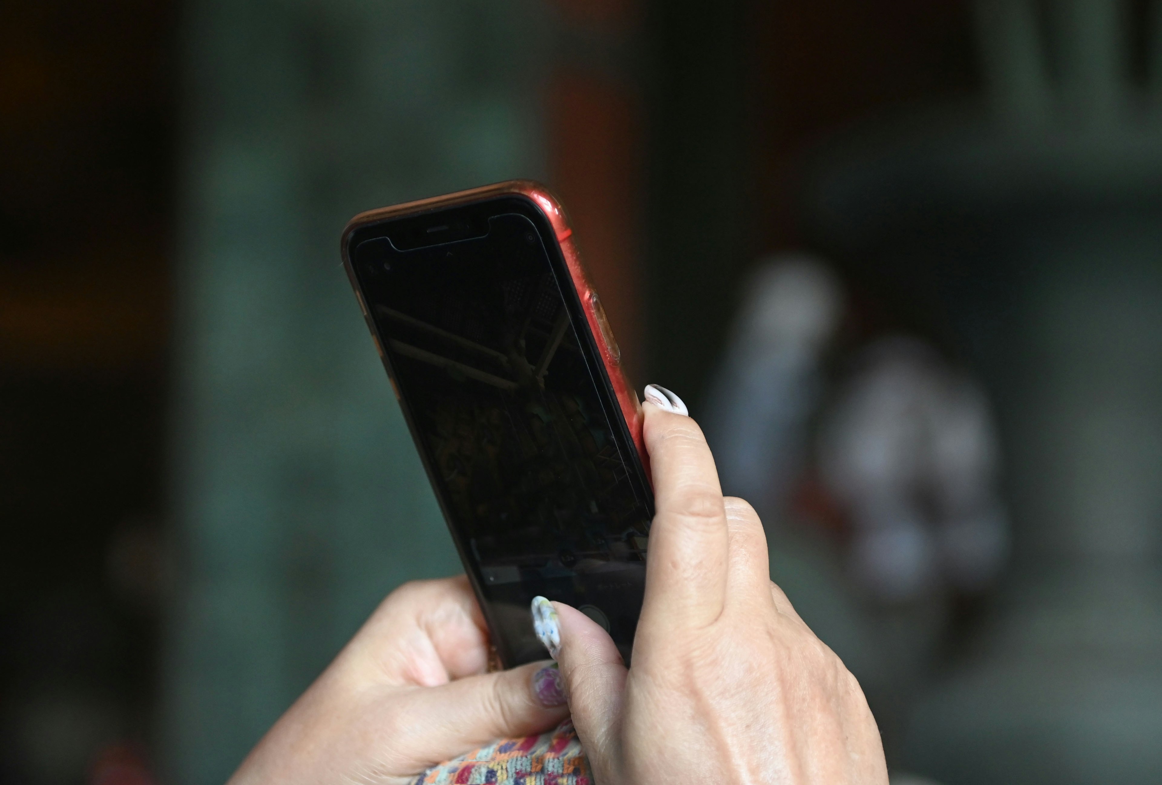 Close-up image of a hand holding a red smartphone