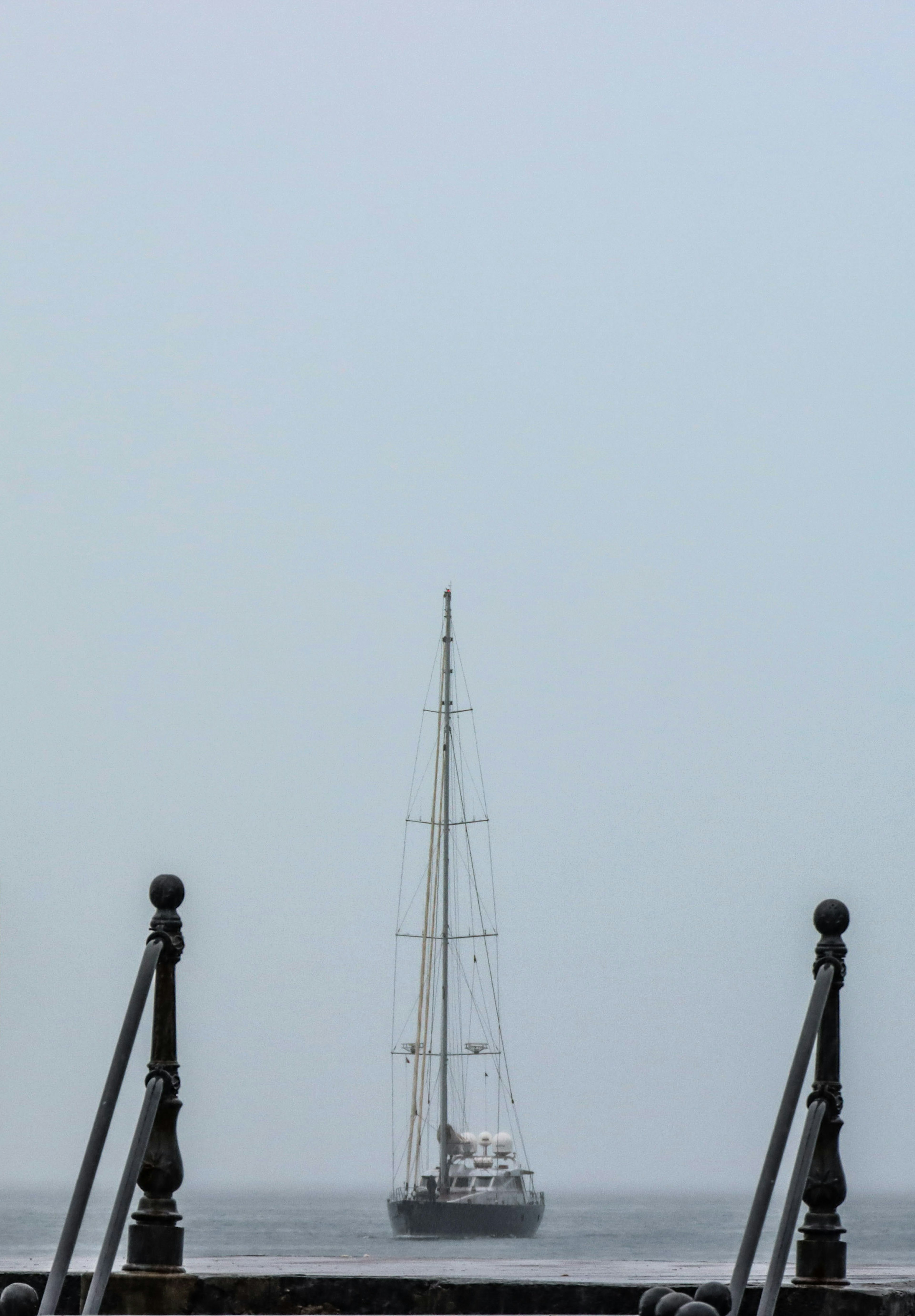 Bateau à voile émergeant dans le brouillard avec vue sur le quai