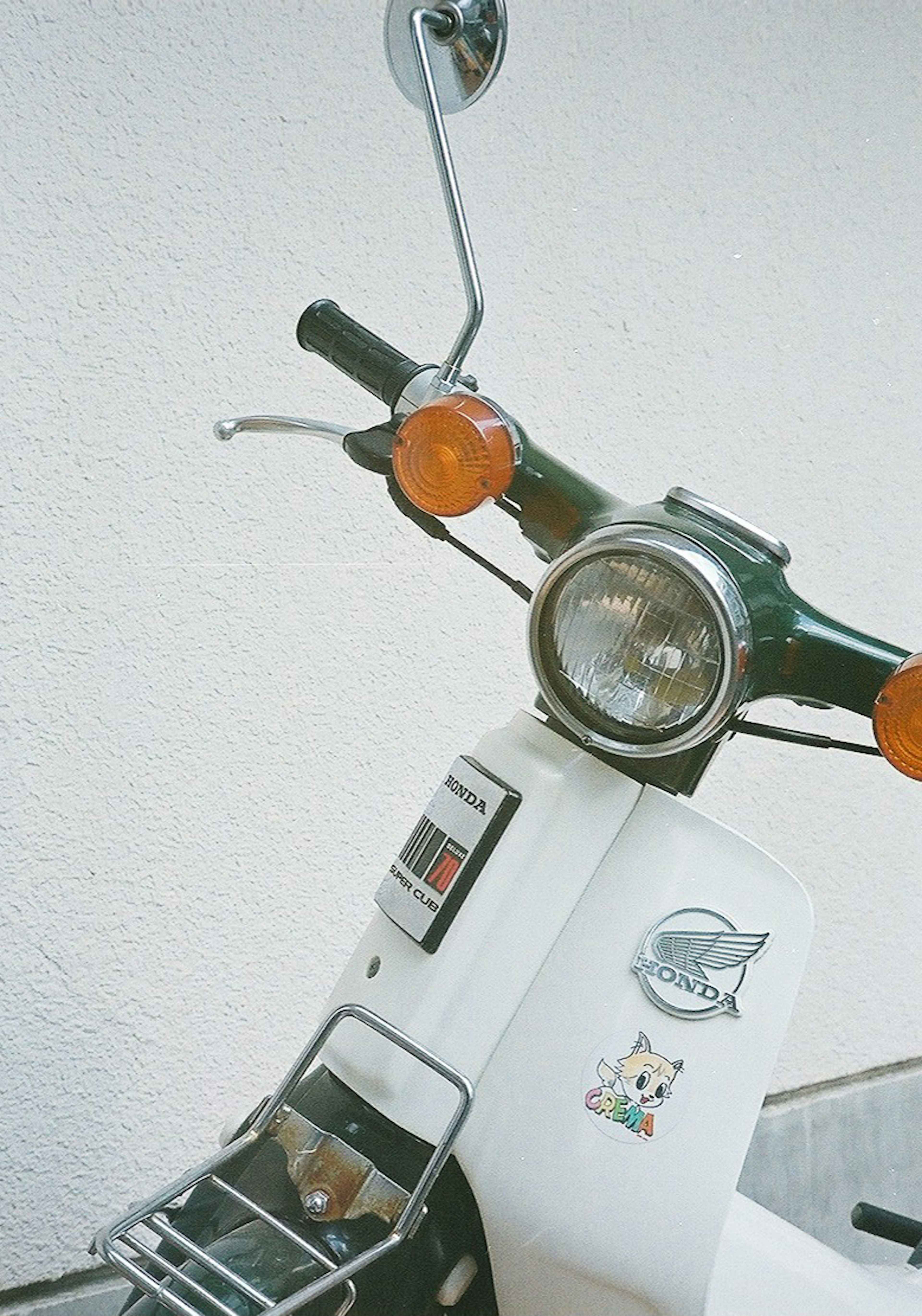 Primer plano del manillar y faro de un scooter blanco con intermitentes naranjas y un diseño simple