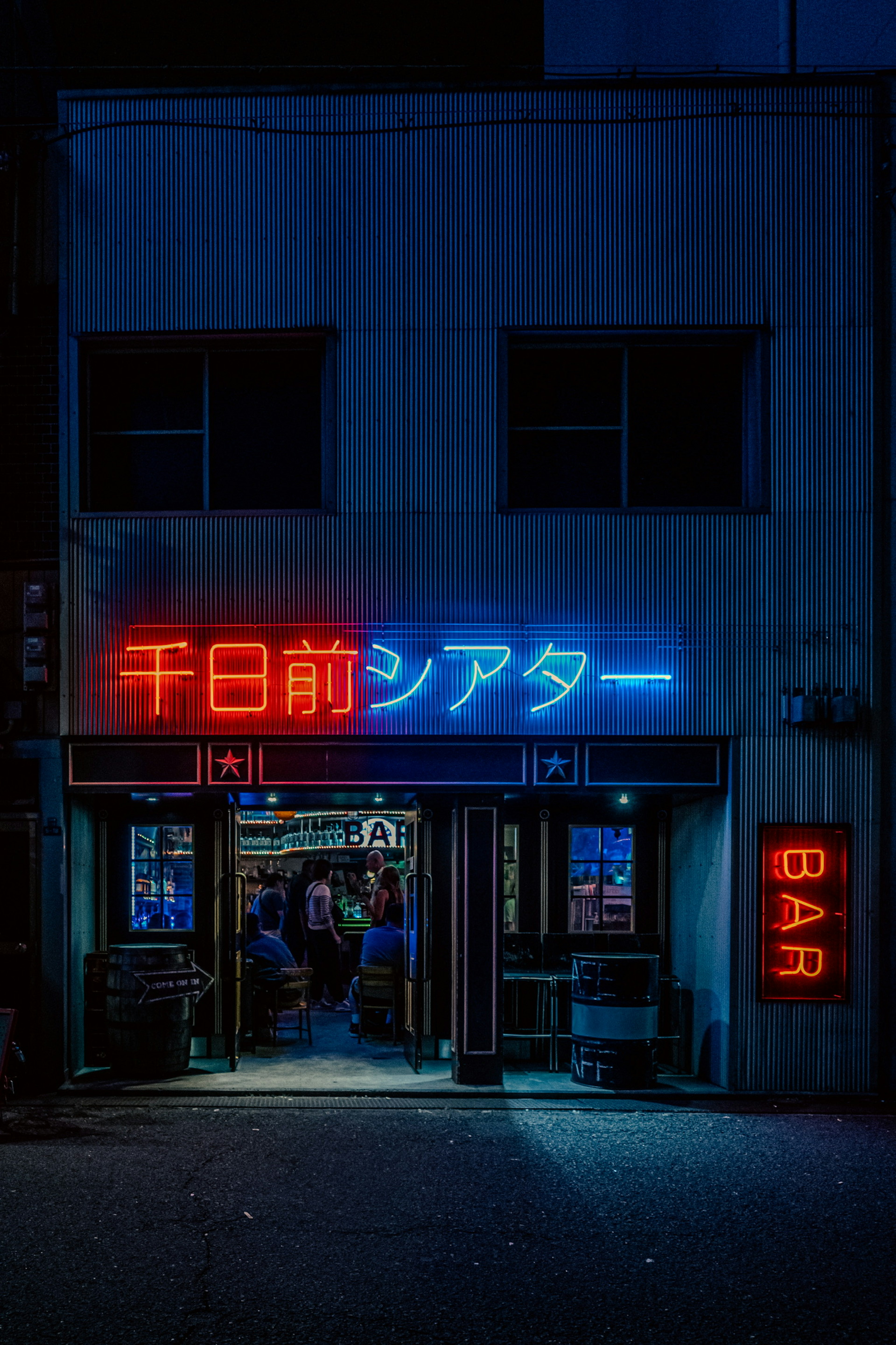 Exterior of a bar featuring blue and red neon signs