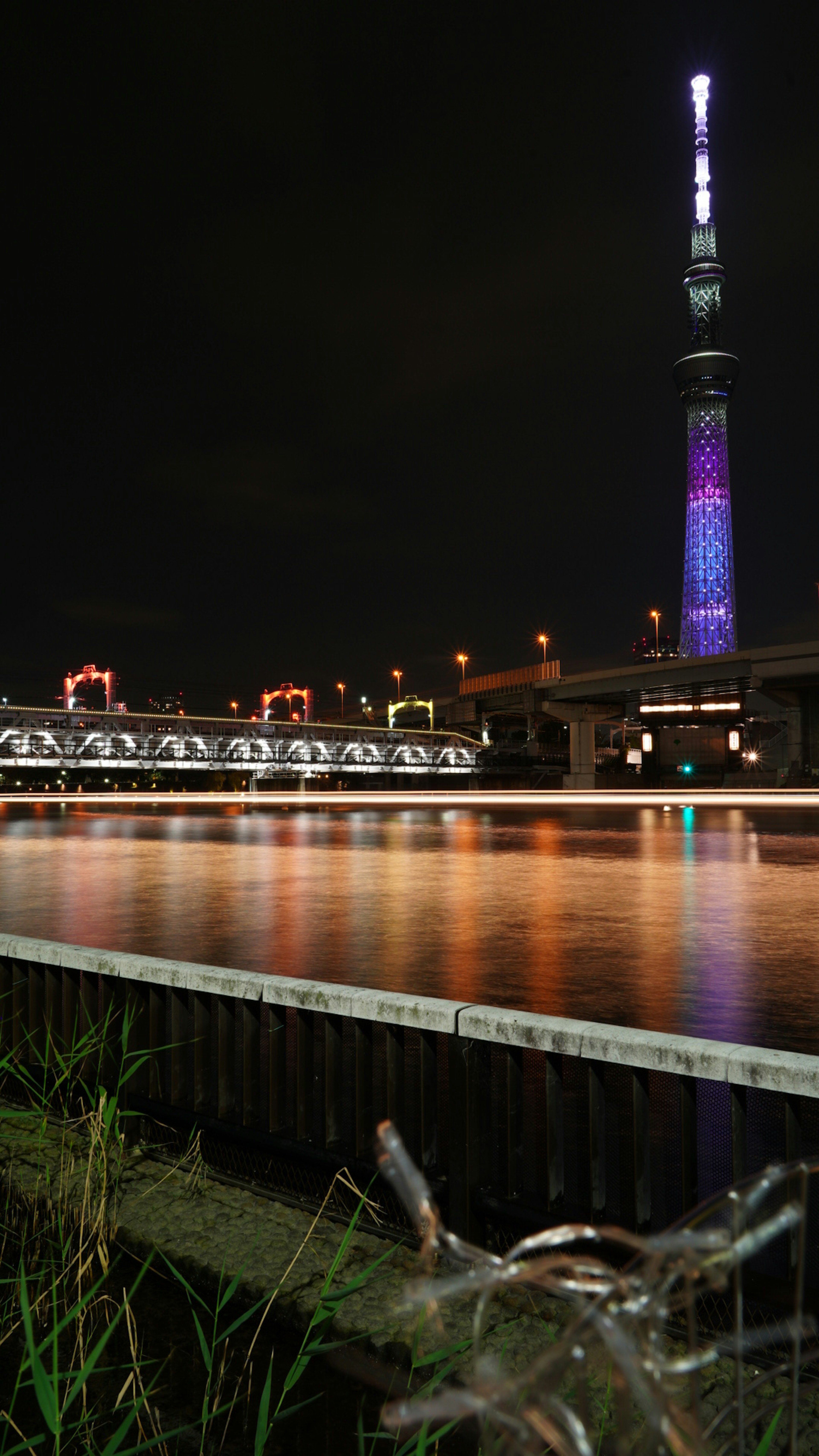 夜の東京スカイツリーと川の景色に反射する光