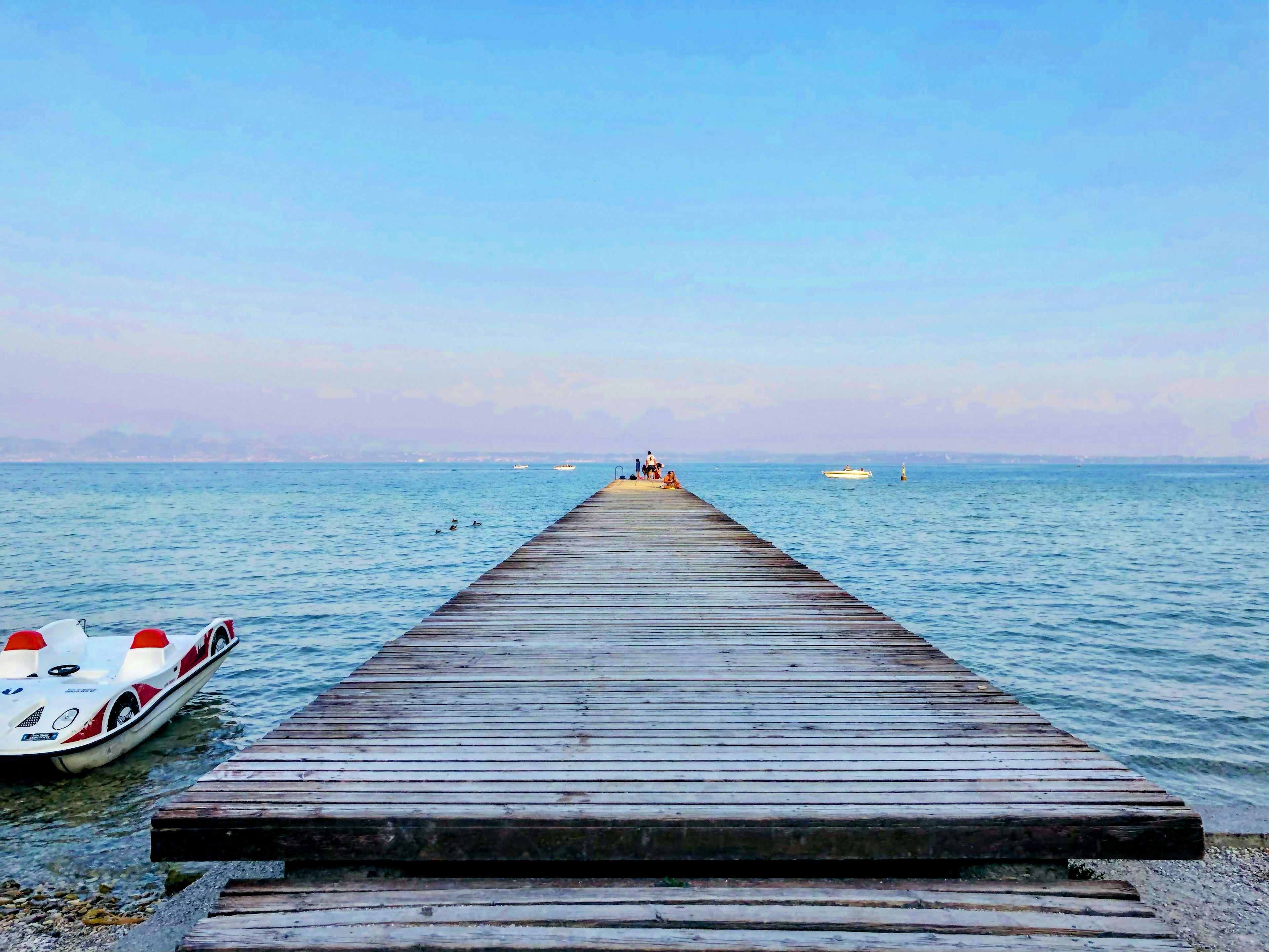 Wooden pier extending into blue water with a tranquil landscape