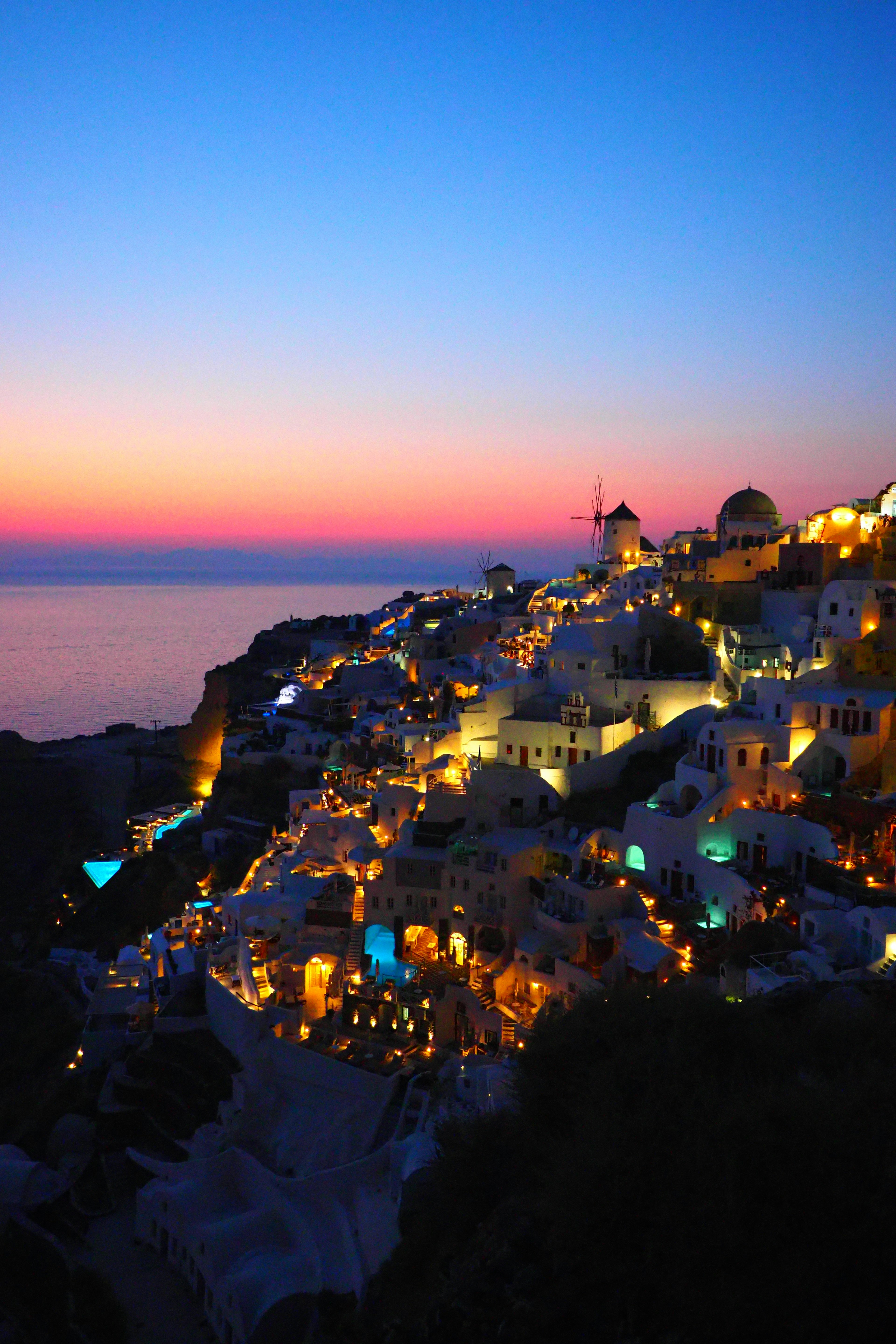 Incantevole costa di Santorini al crepuscolo con luci scintillanti