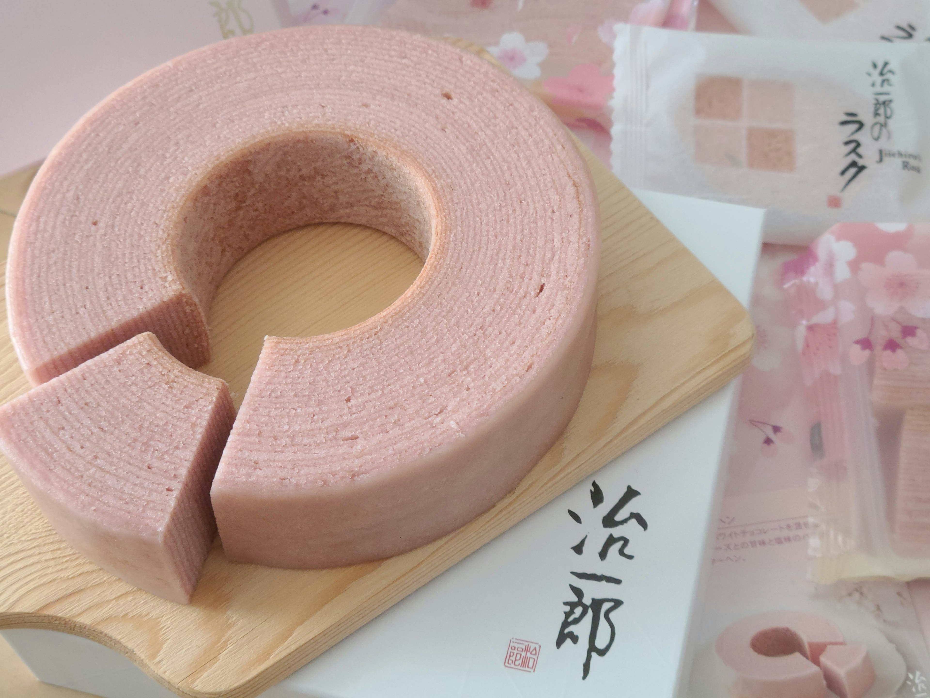 Bánh baumkuchen màu hồng trên đĩa gỗ