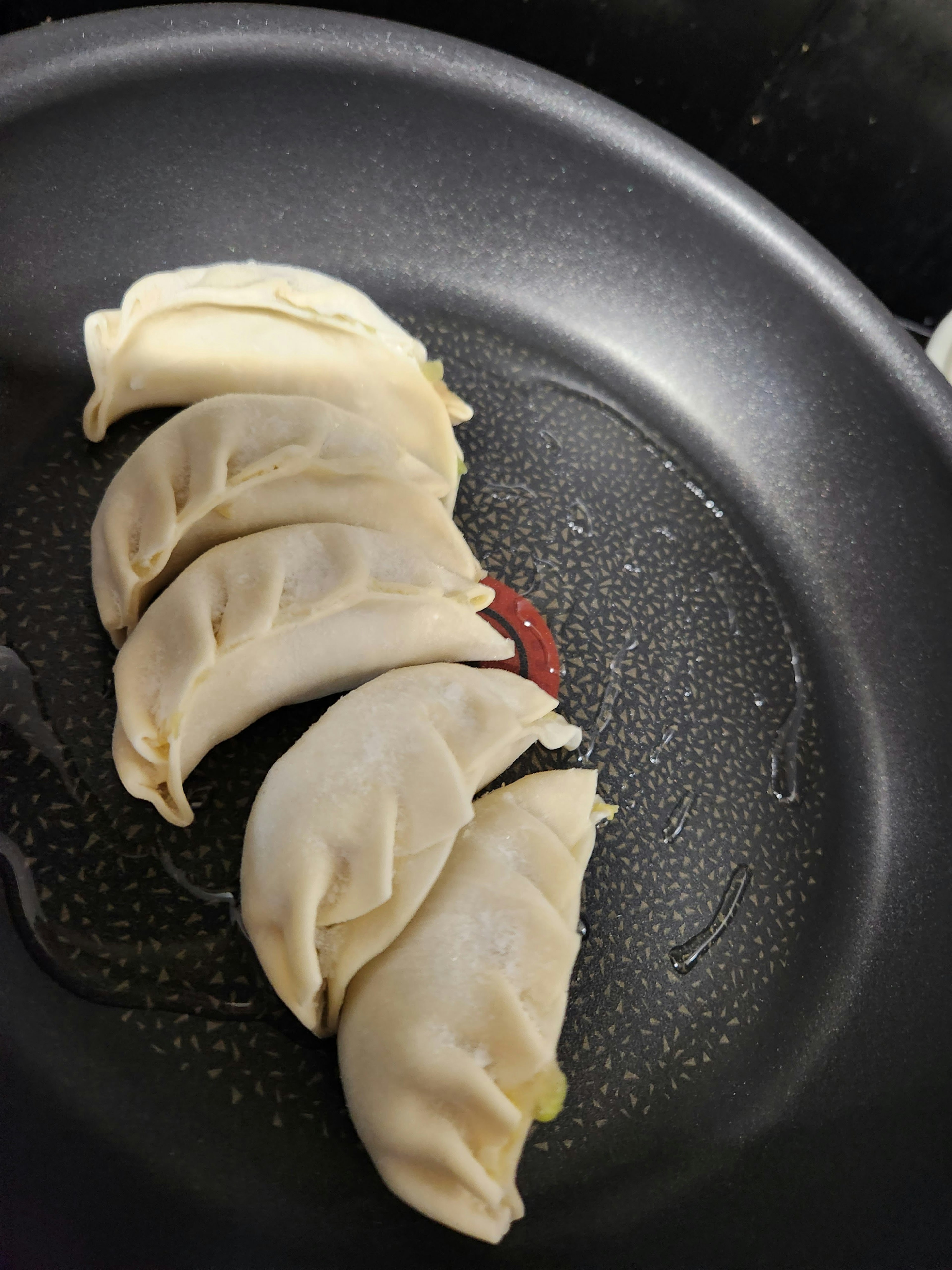 A close-up of dumplings arranged in a frying pan