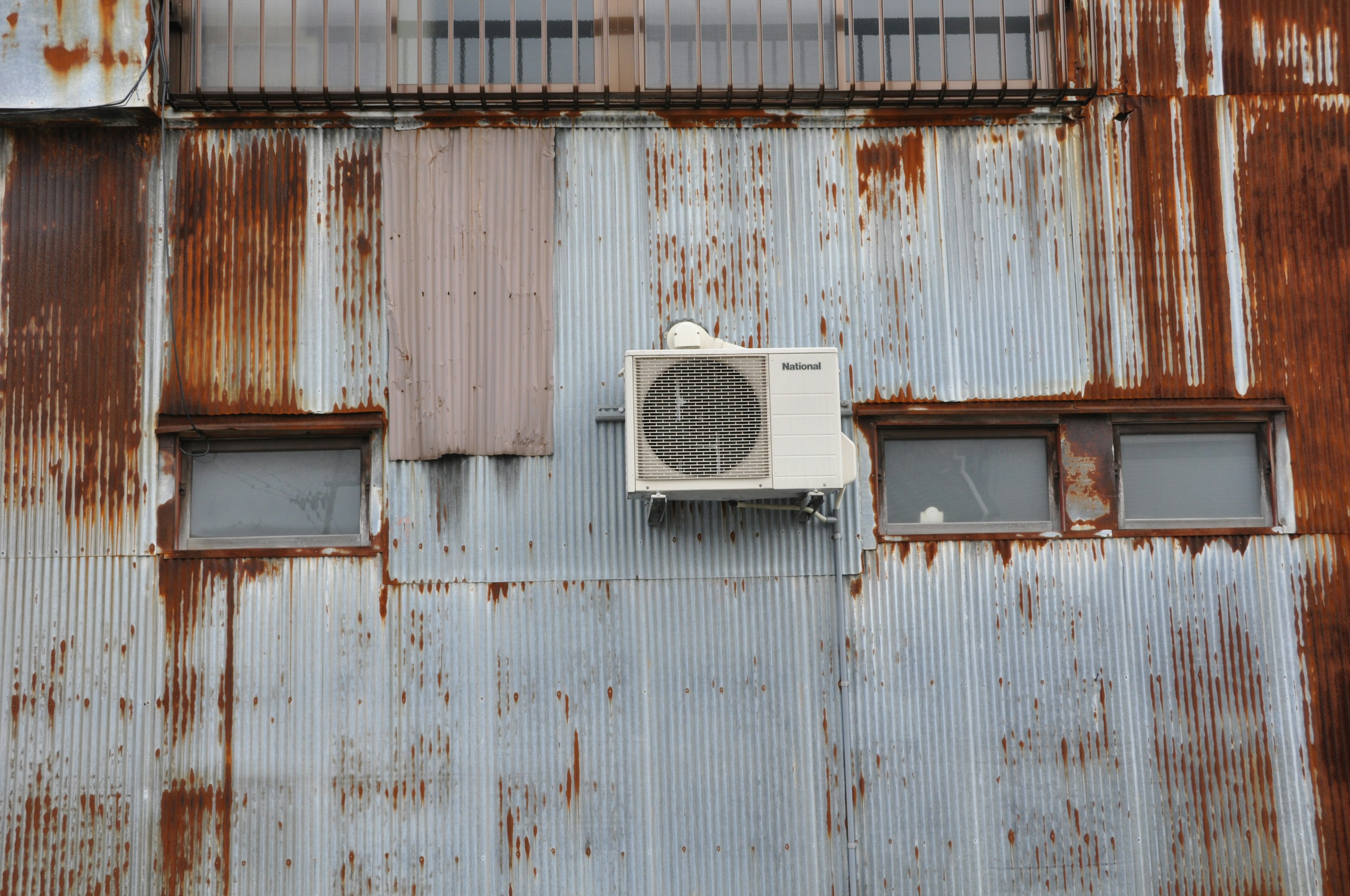 Rusty metal wall with an air conditioning unit and windows