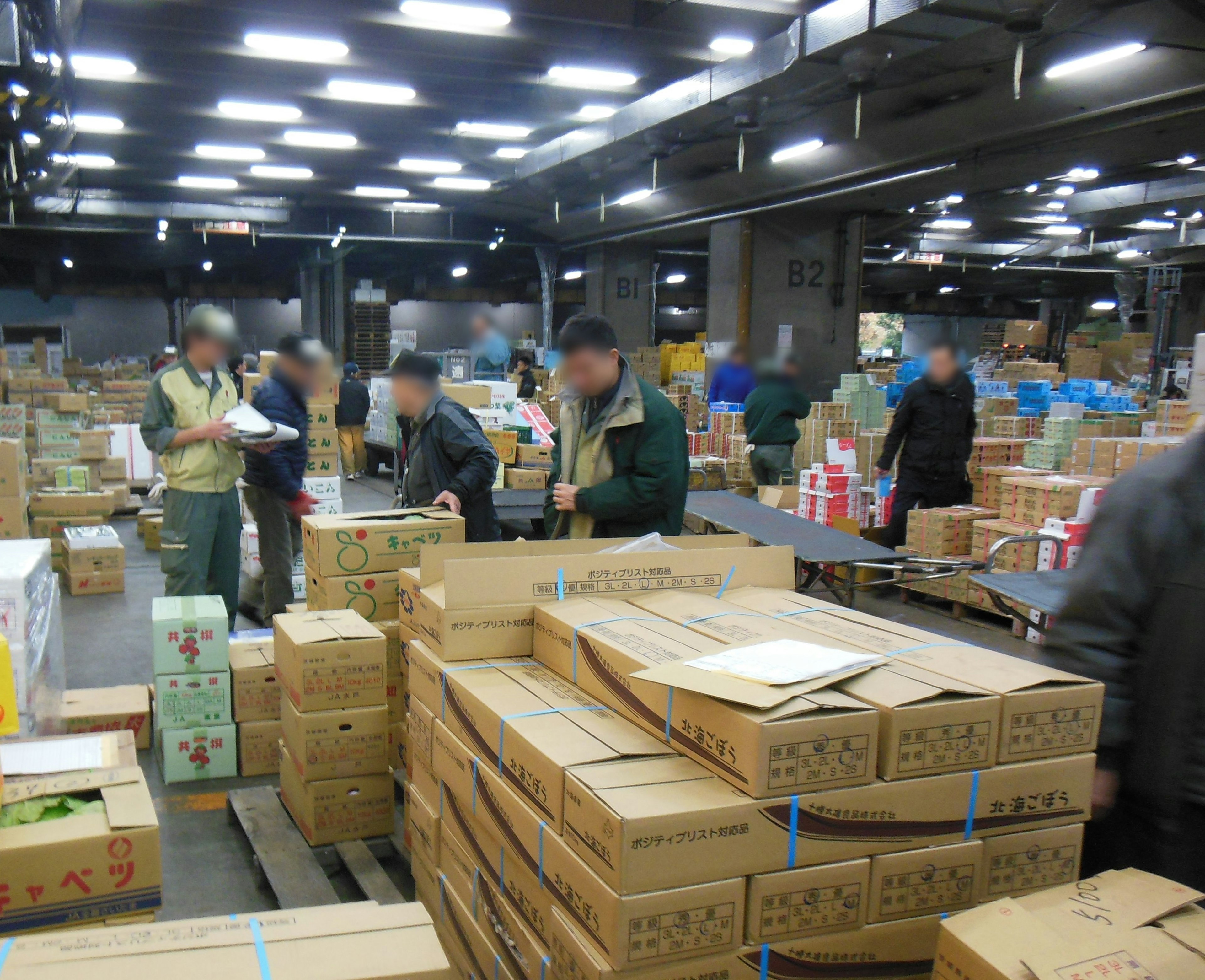 Warehouse scene with people working among stacked boxes