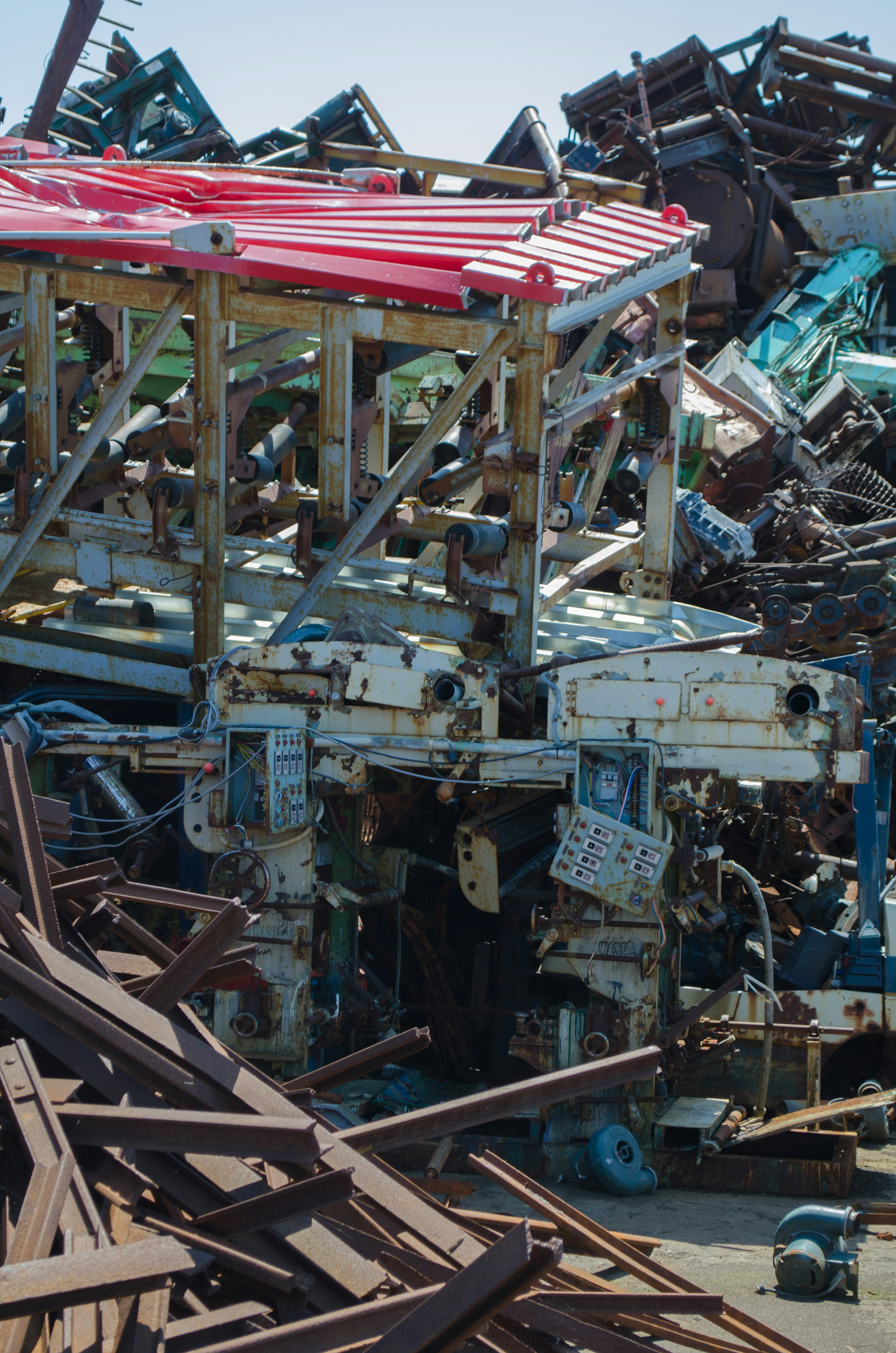 Old machinery surrounded by piles of scrap material featuring a distinctive red roof