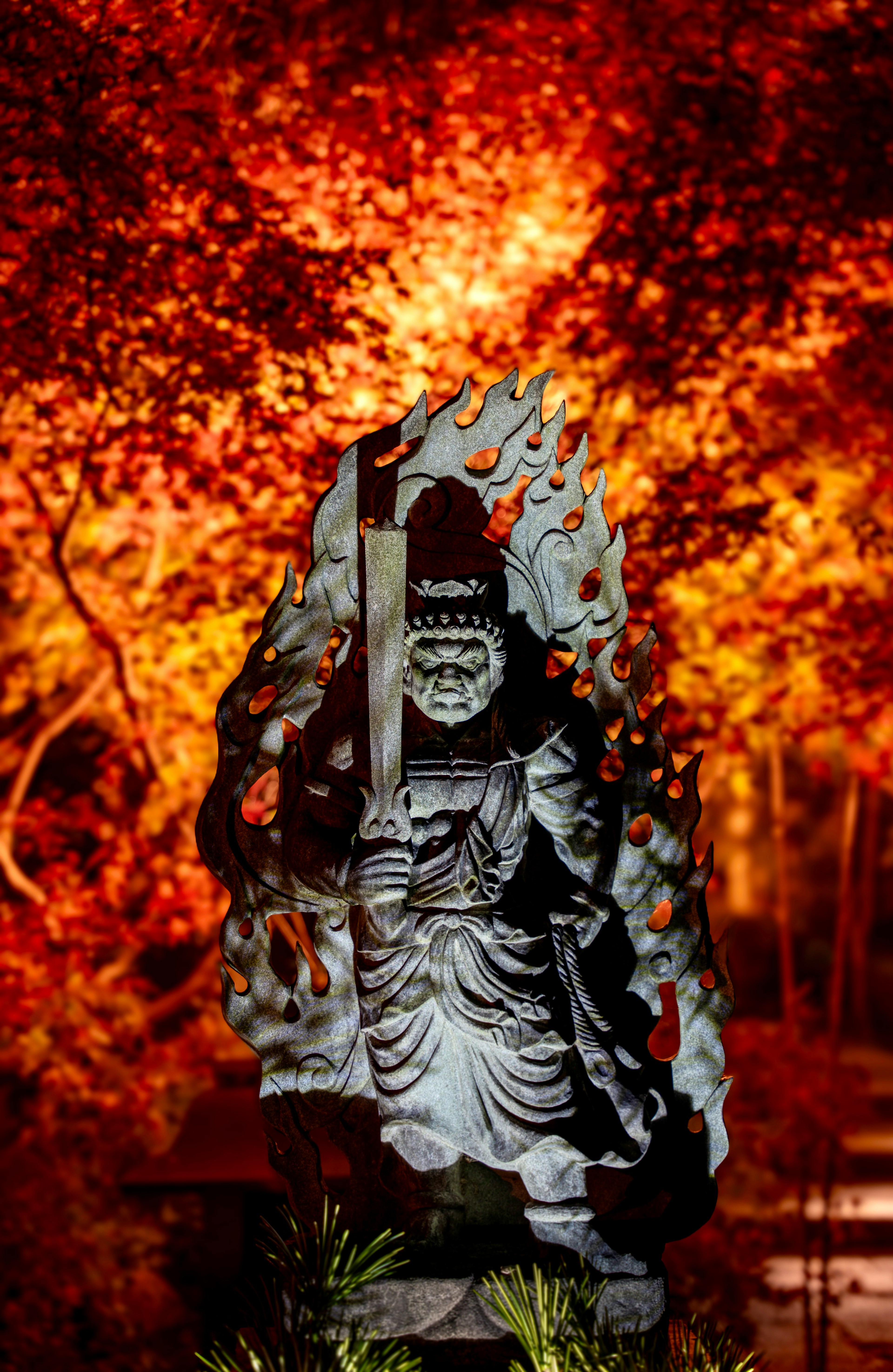 Sculpture of a deity with vibrant autumn foliage in the background