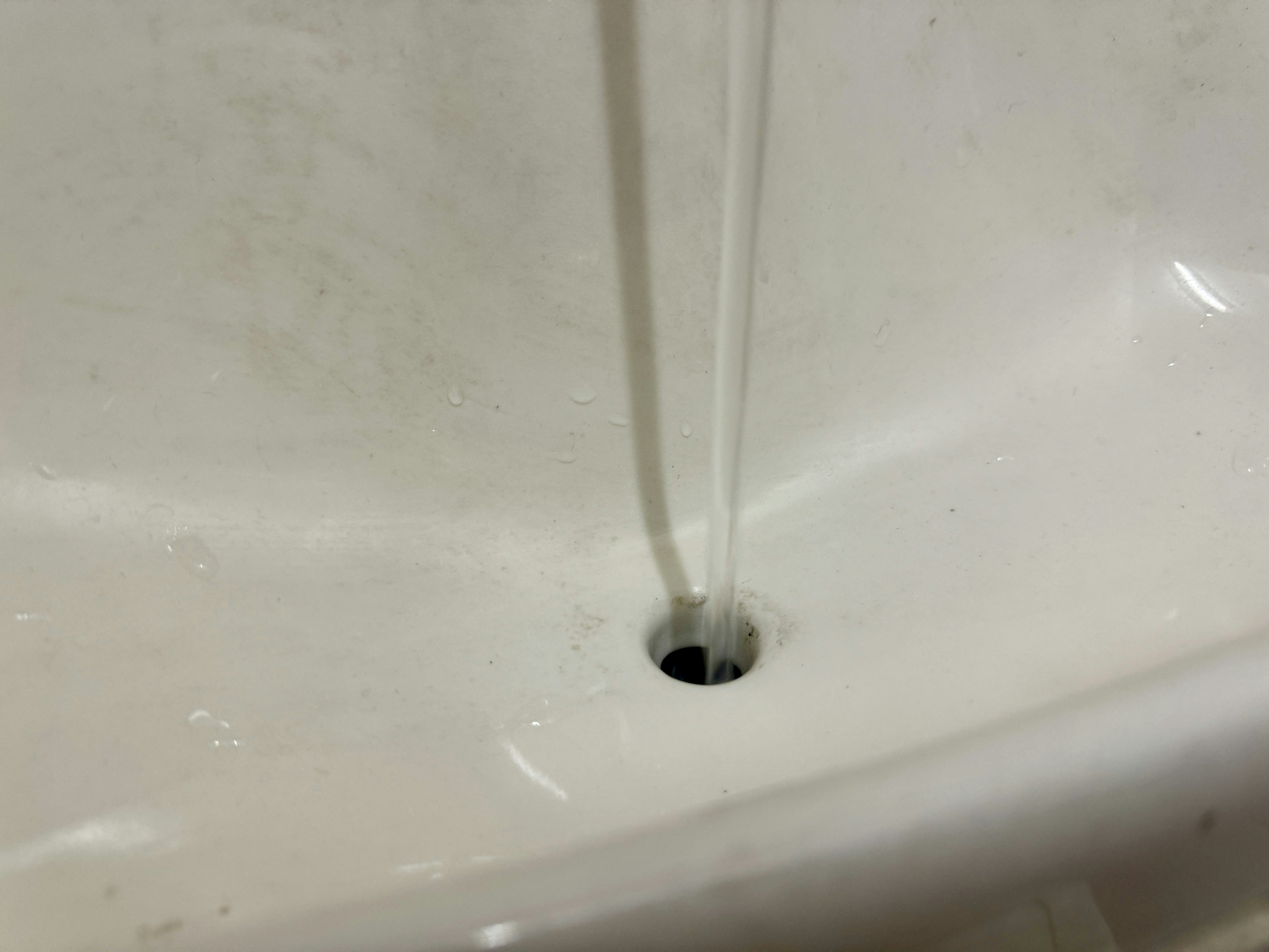 Water flowing into a white sink with a drain hole