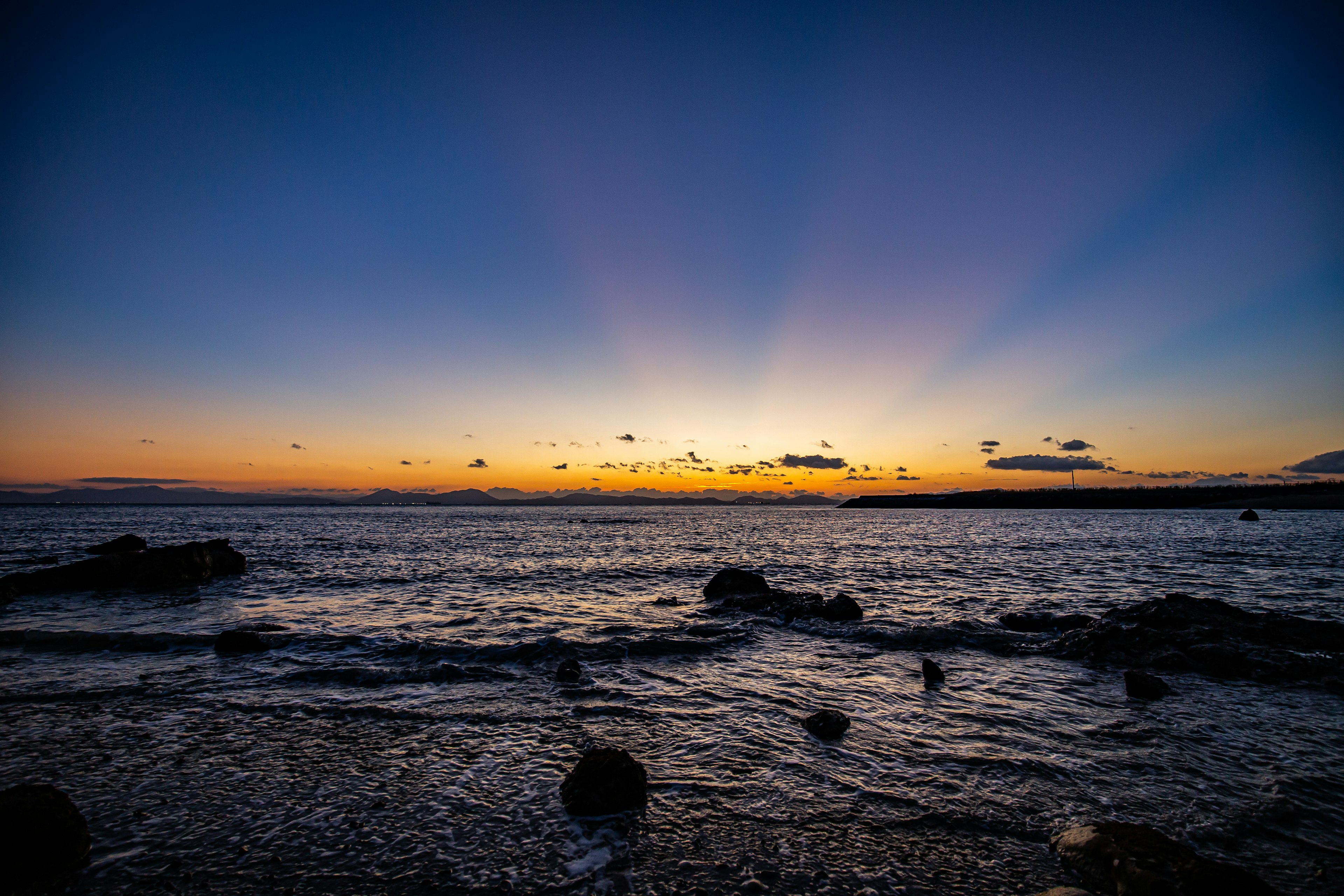 Un paesaggio marino bellissimo con tramonto e raggi di luce nel cielo blu