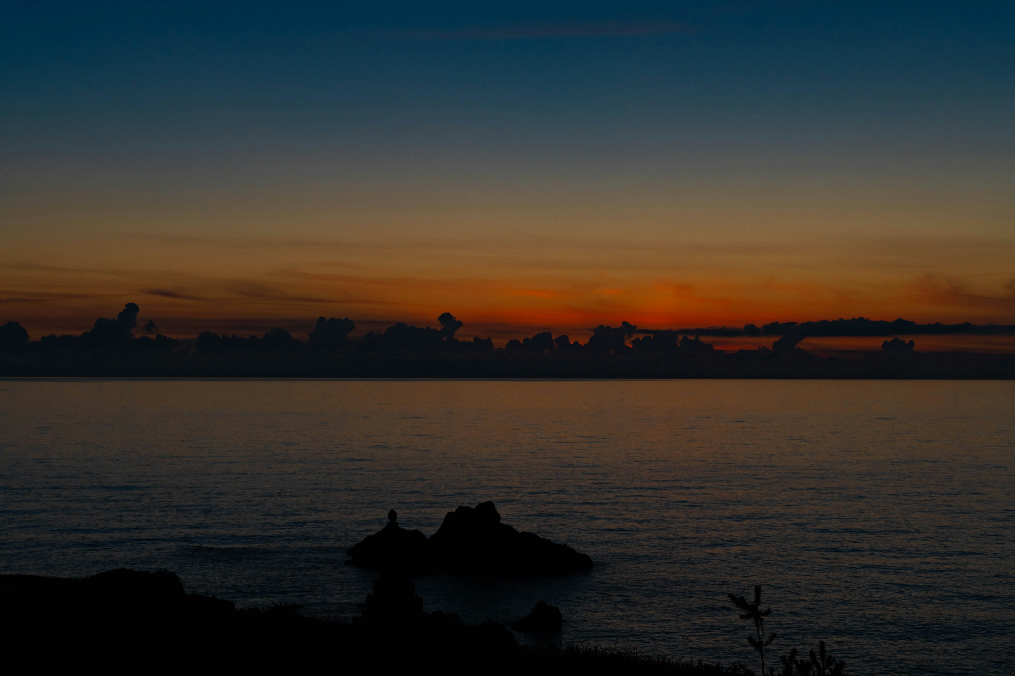 Calm sea with a sunset and silhouetted rocks