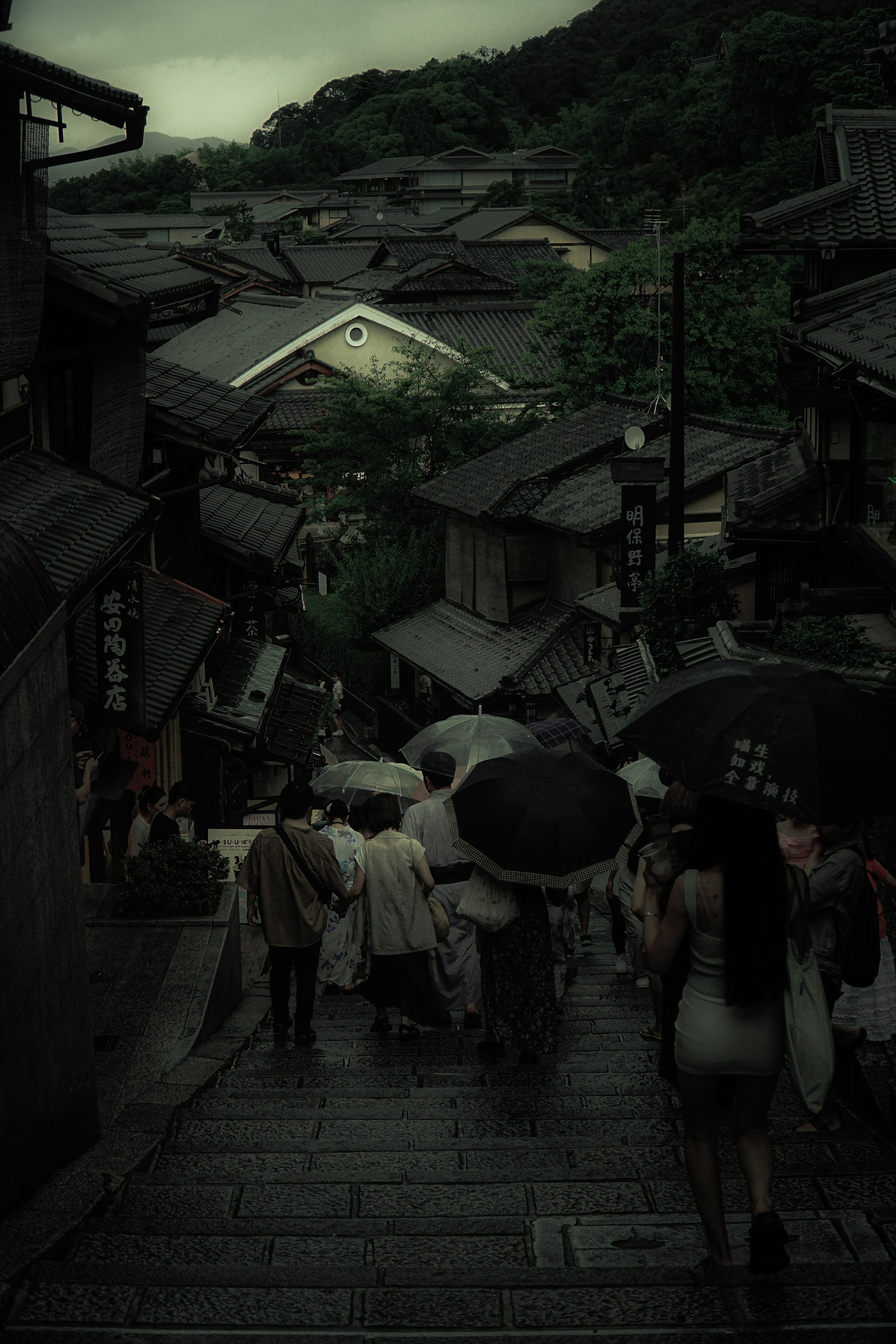 Des gens marchant sous la pluie avec des parapluies et des bâtiments traditionnels en vue