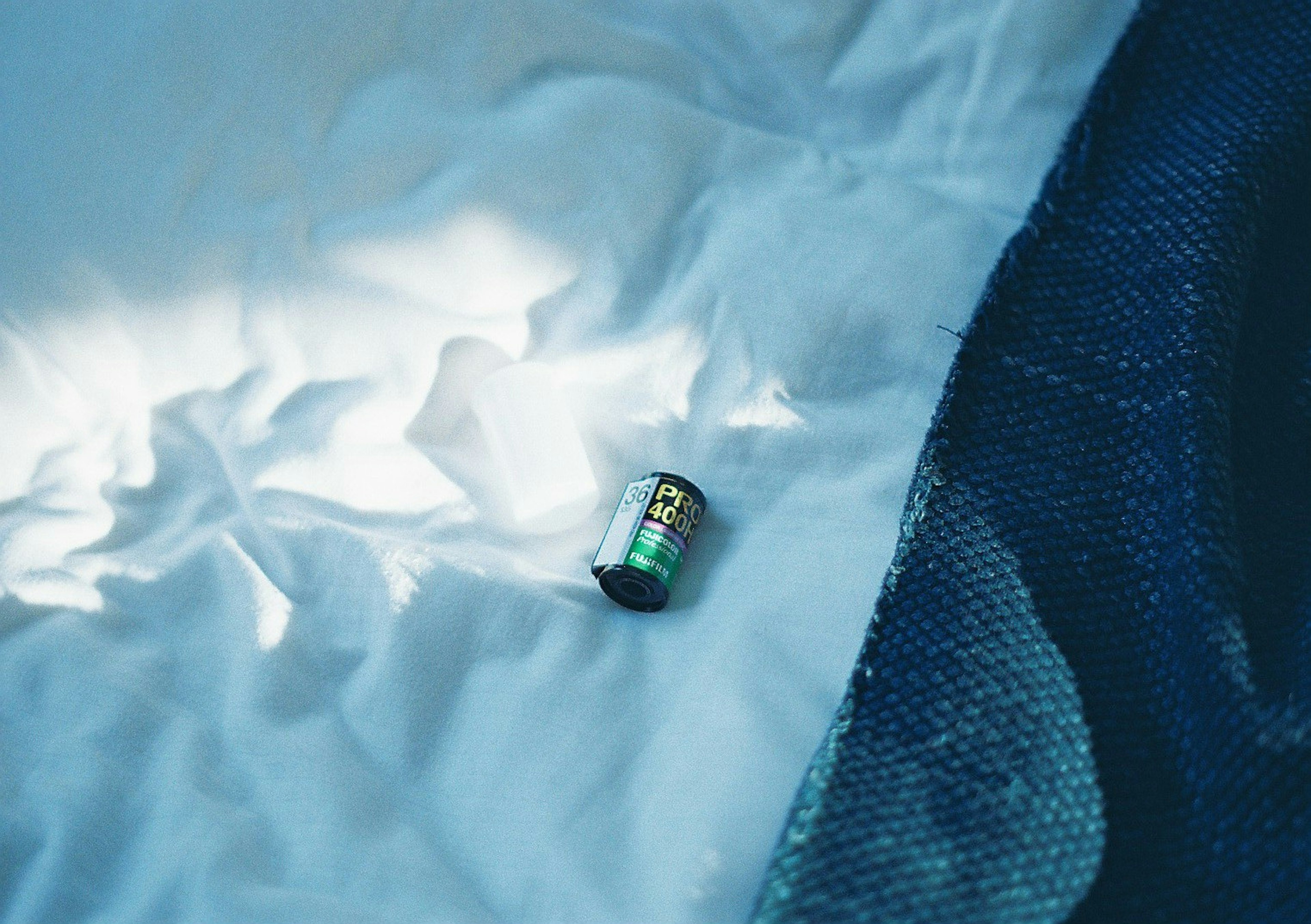 A small battery resting on white fabric with a blue fabric section visible