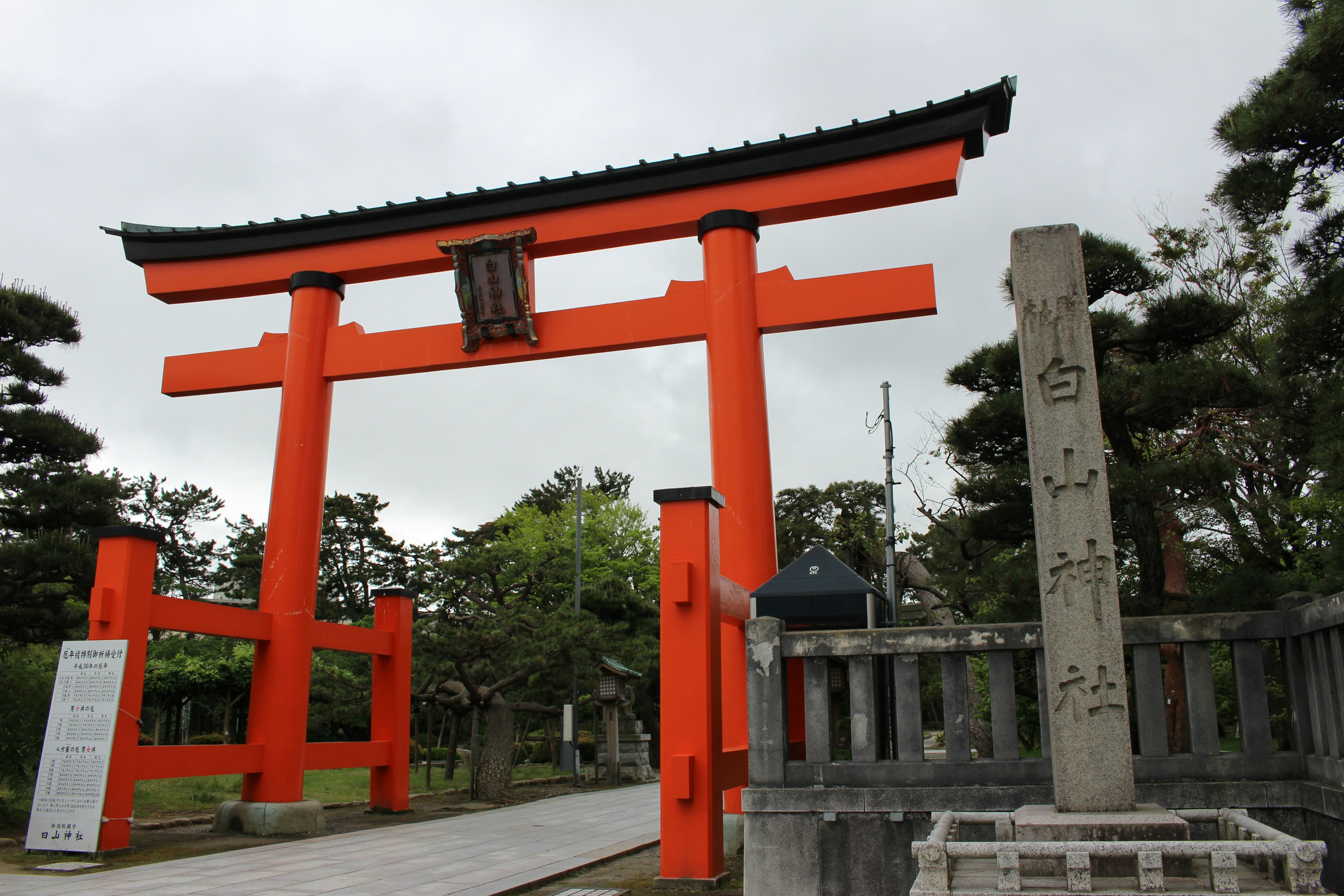 Eingang eines Schreins mit einem roten Torii und einem Steindenkmal