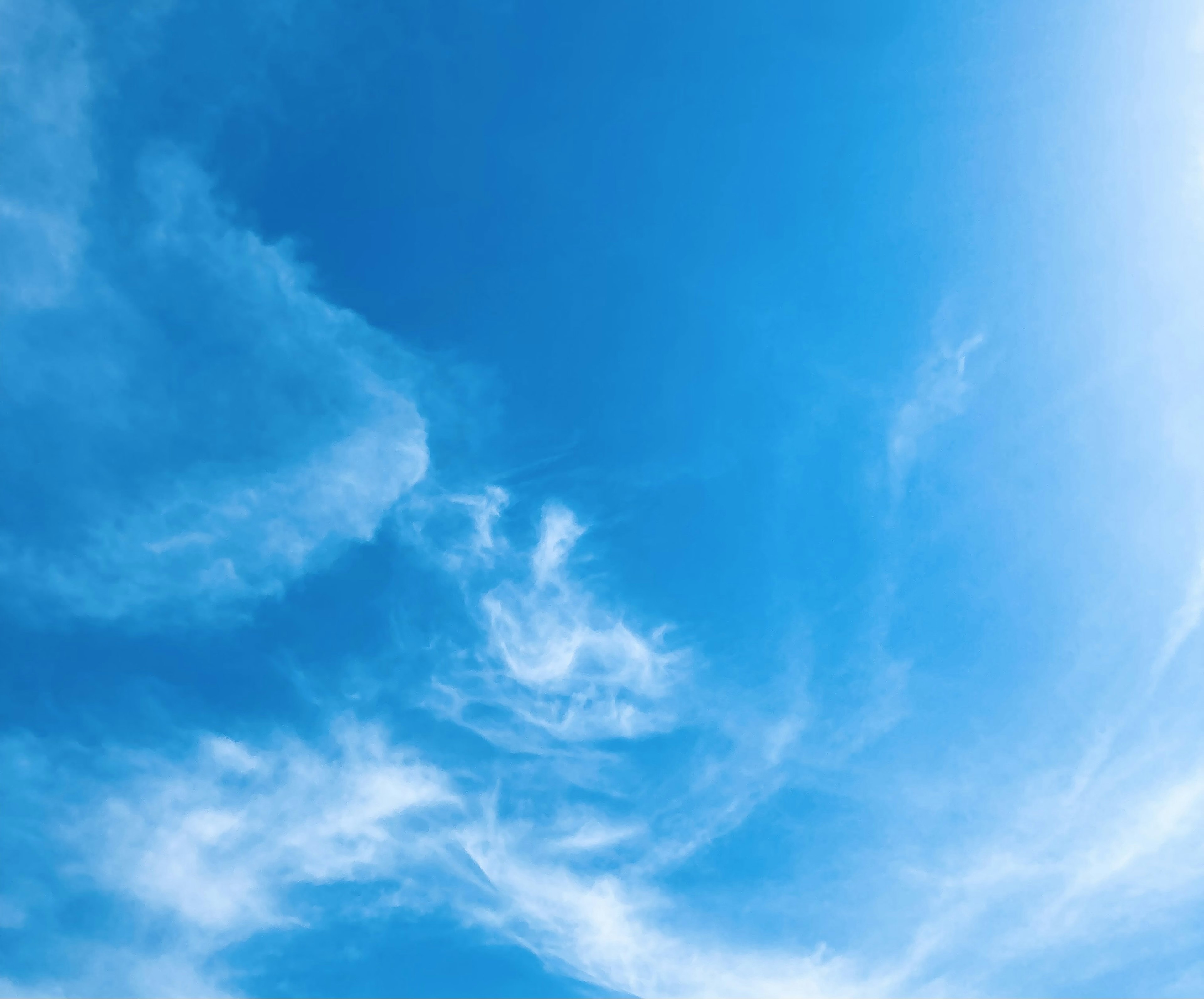 Vast blue sky with wispy white clouds