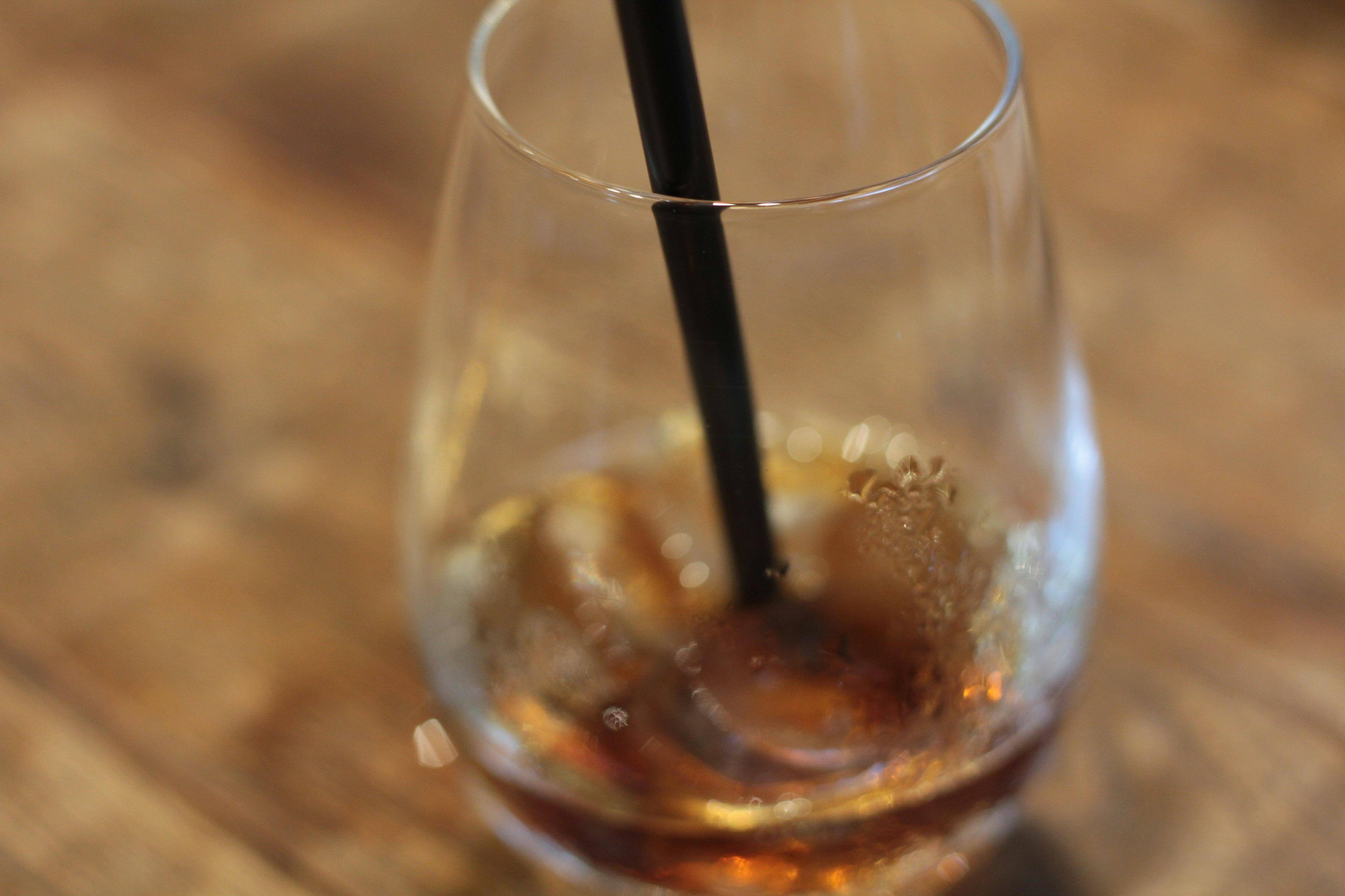 Glass with drink and ice featuring a black straw