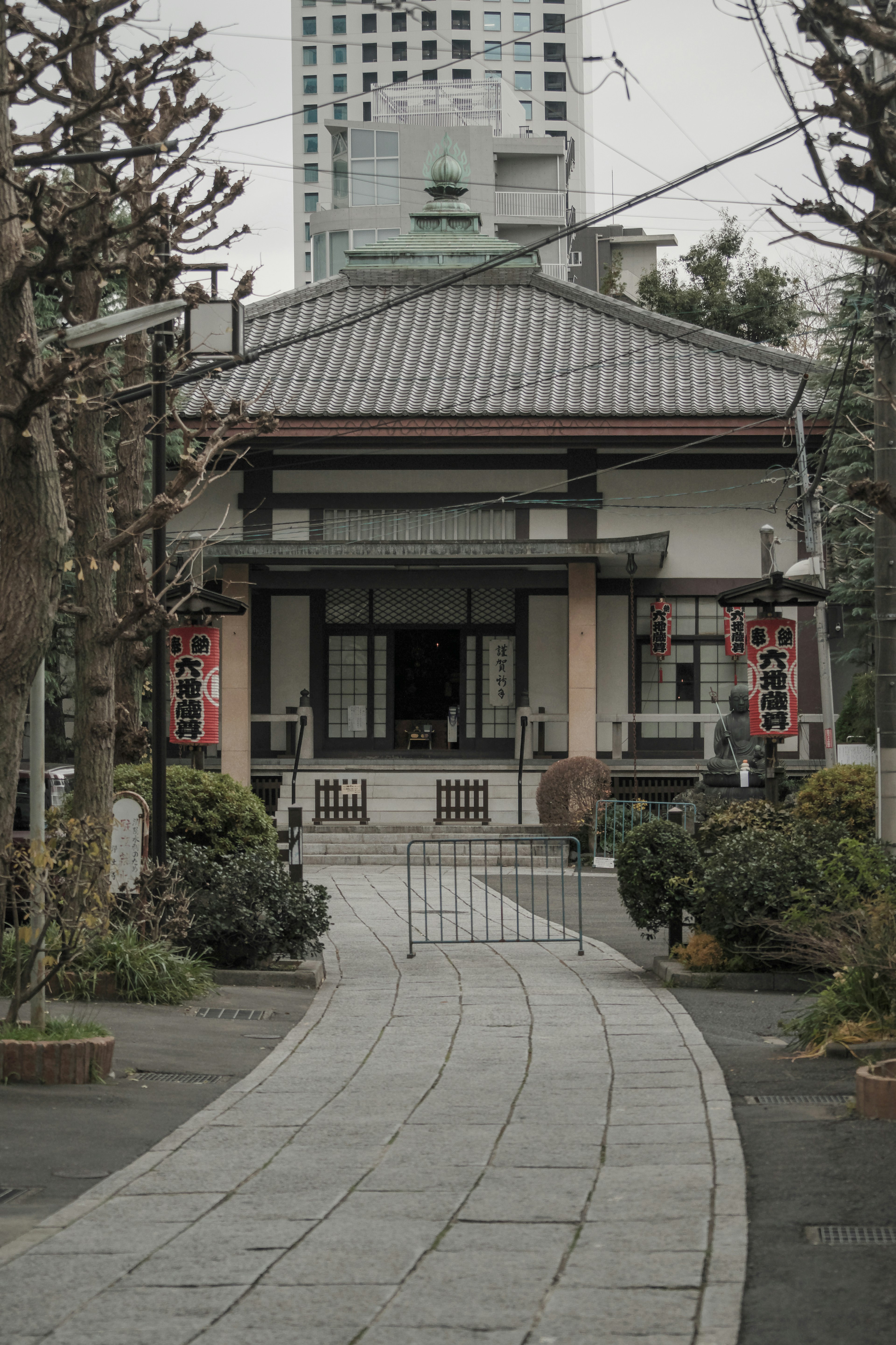 Maison japonaise traditionnelle entourée de verdure avec un chemin en pierre et une porte visibles