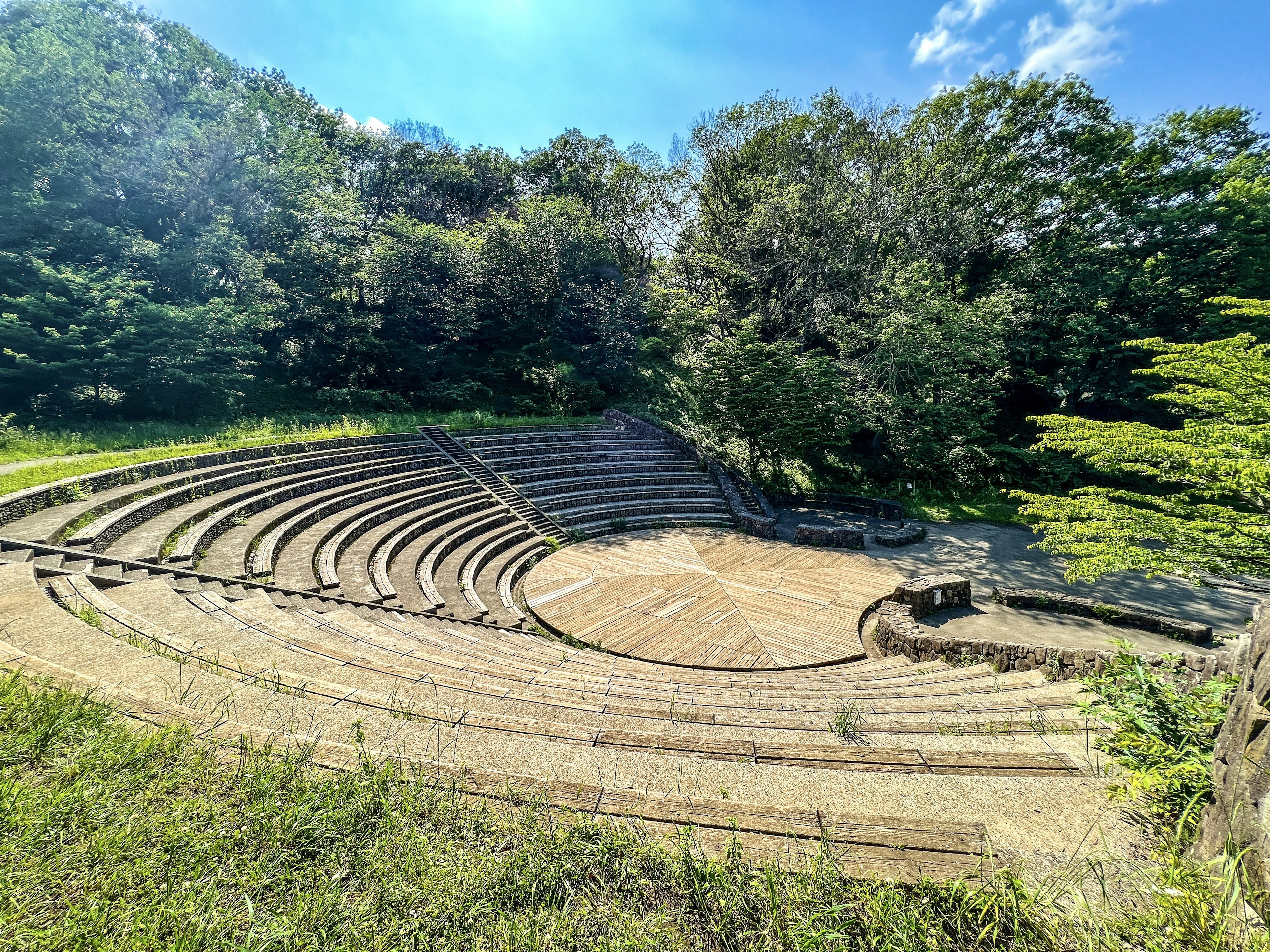 Circular amphitheater surrounded by lush greenery and blue sky