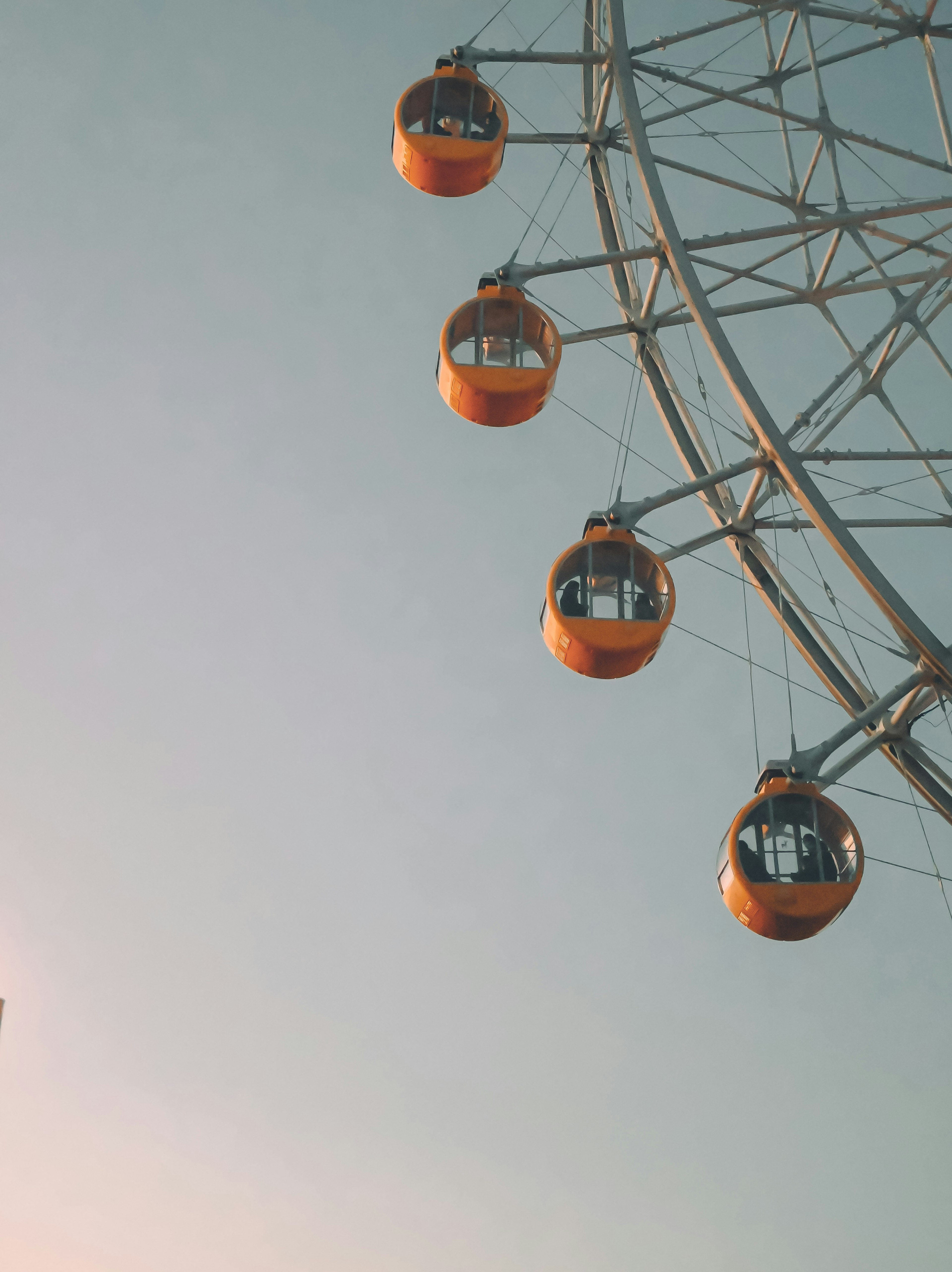 Orangefarbene Kapseln eines Riesenrads vor blauem Himmel