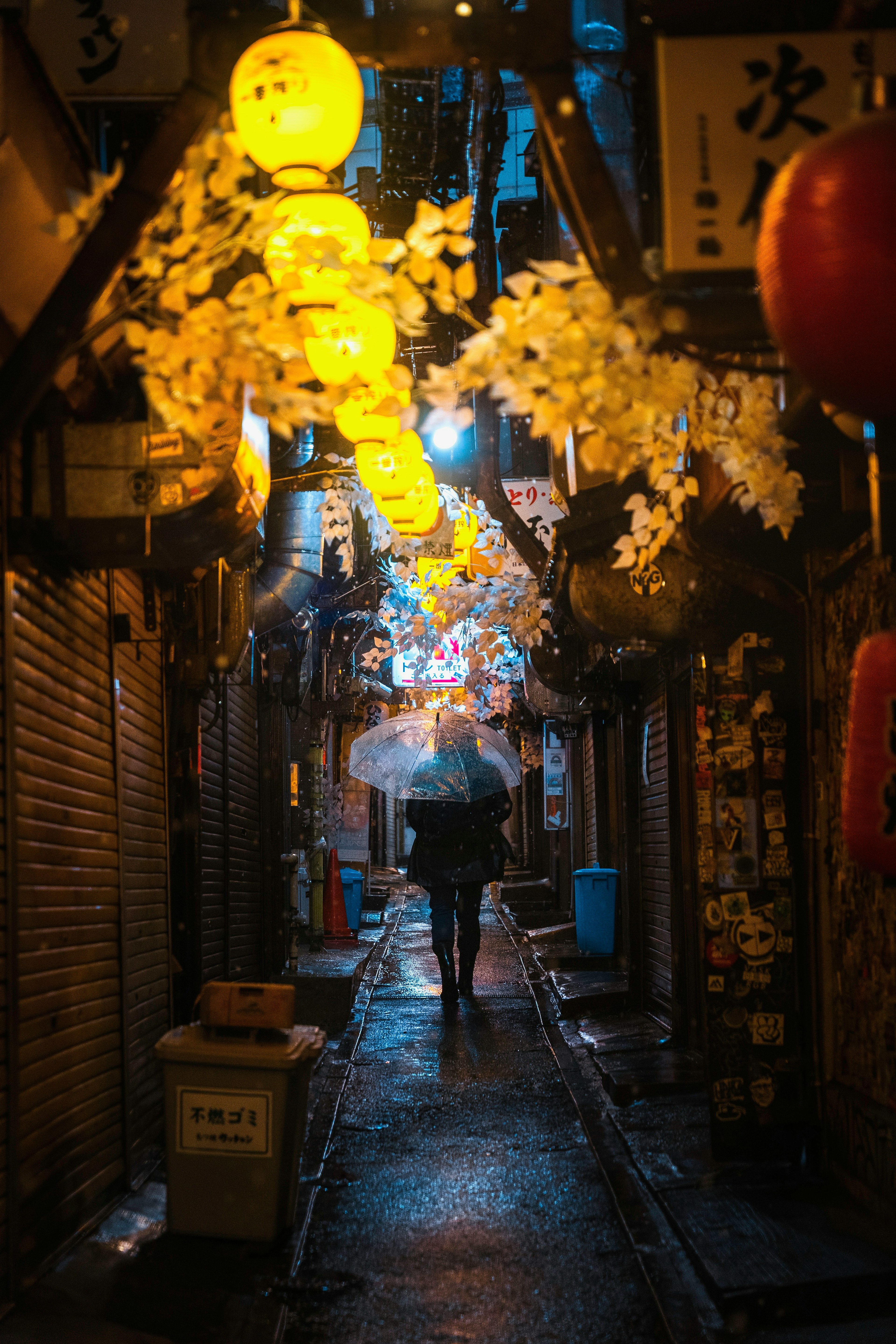 Una persona caminando bajo faroles en un callejón estrecho bajo la lluvia