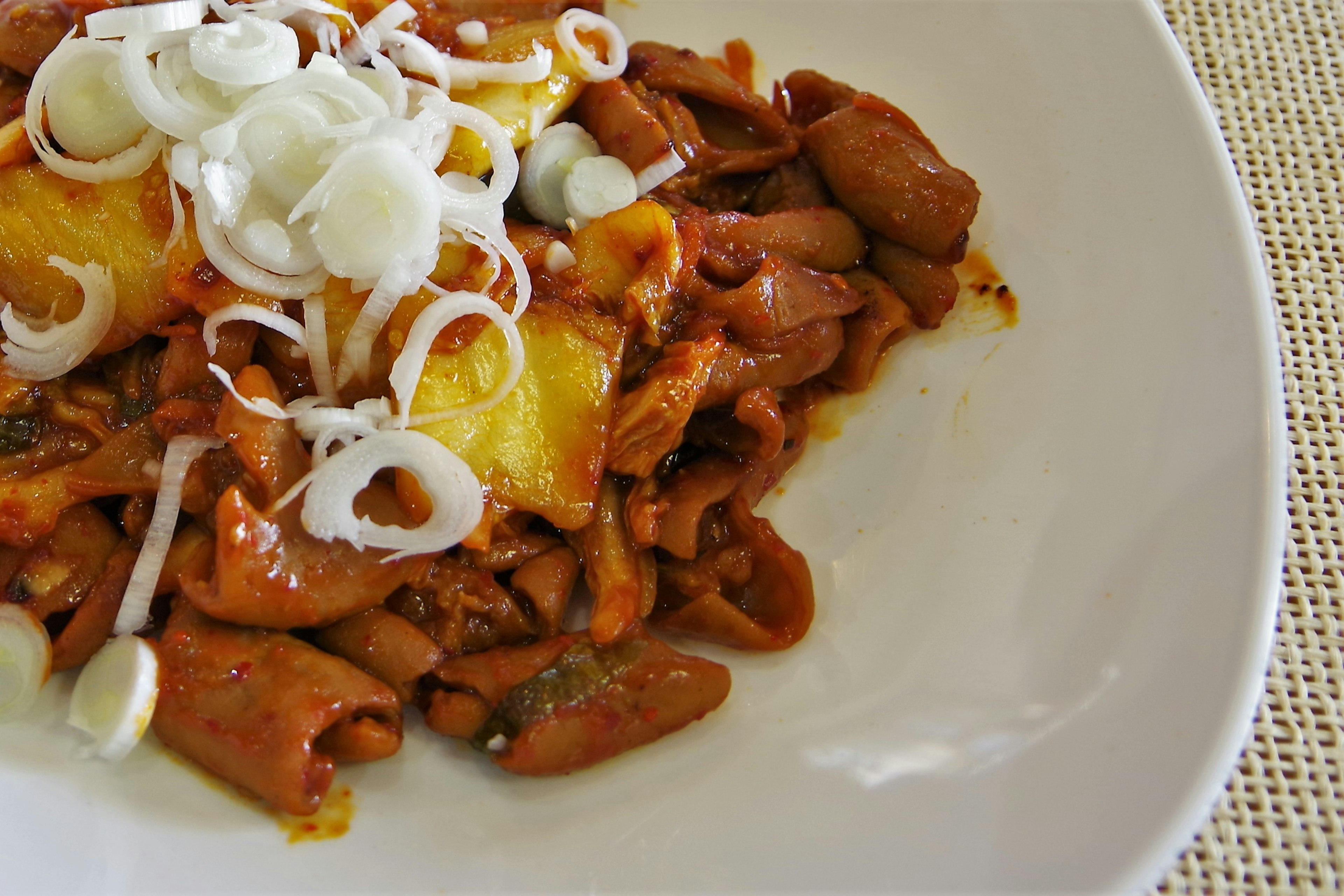 Une assiette de pâtes dans une sauce rouge garnie d'oignons blancs tranchés