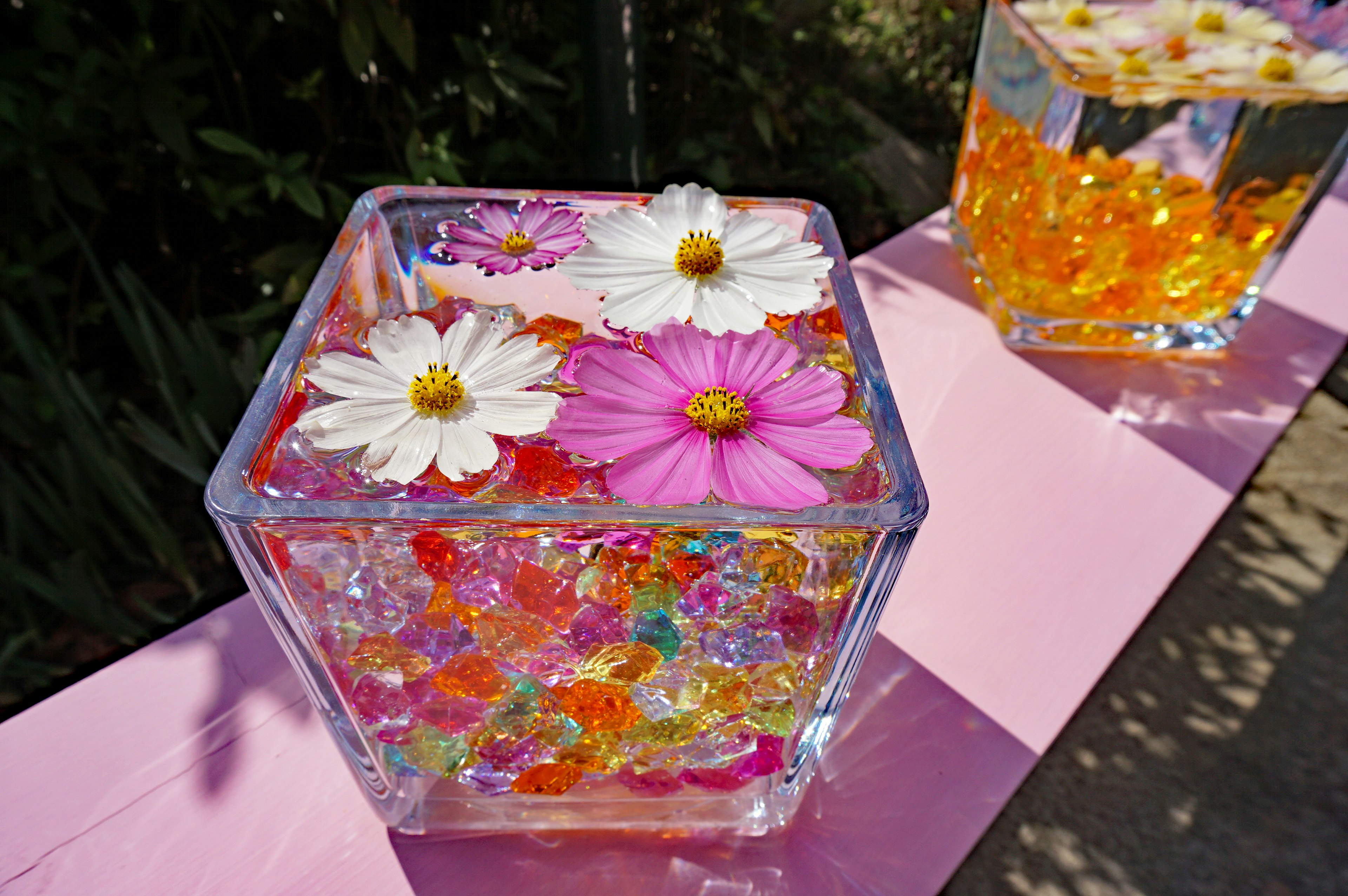 Clear container filled with colorful beads and floating flowers