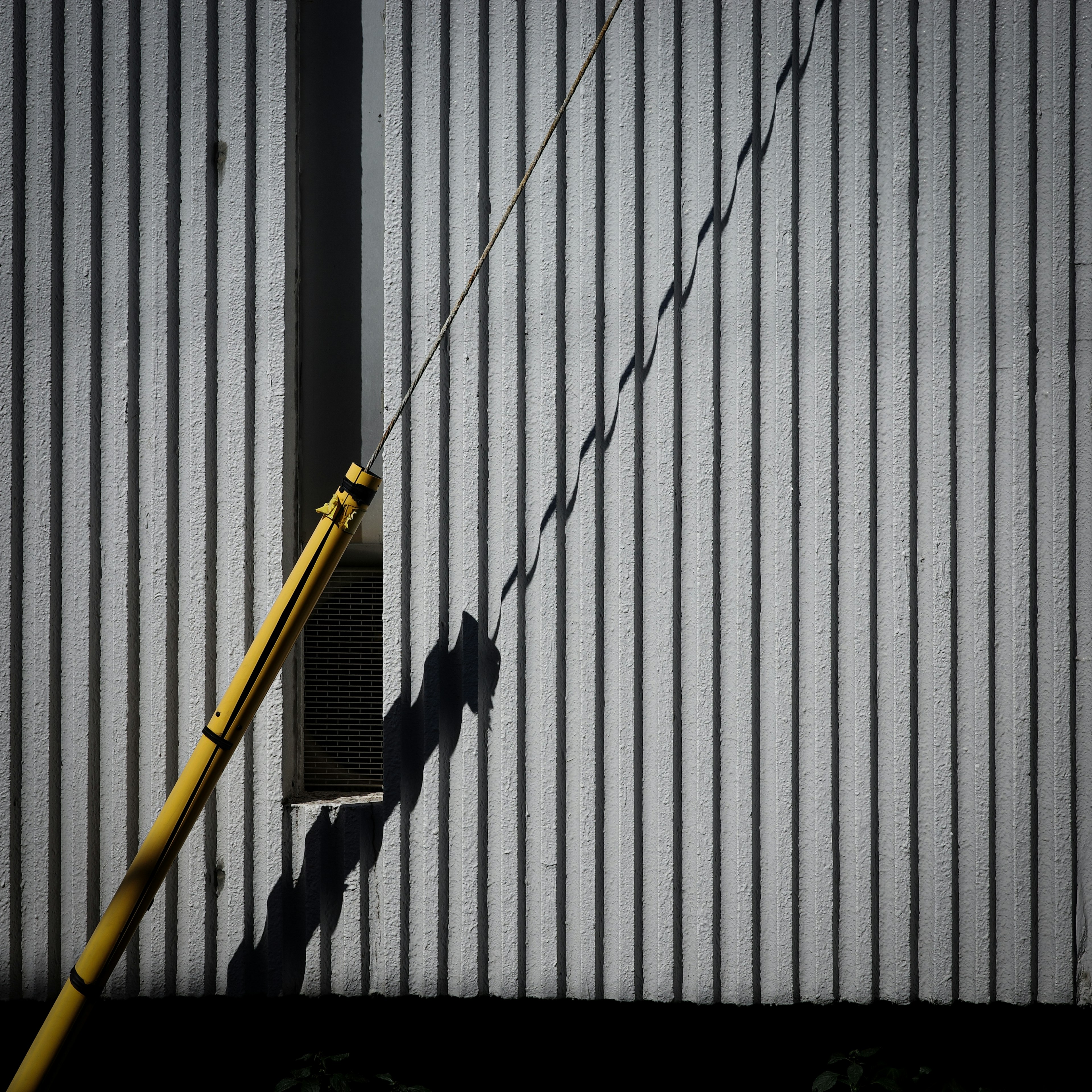 Gelbe Krane werfen Schatten auf gestreifte Wand