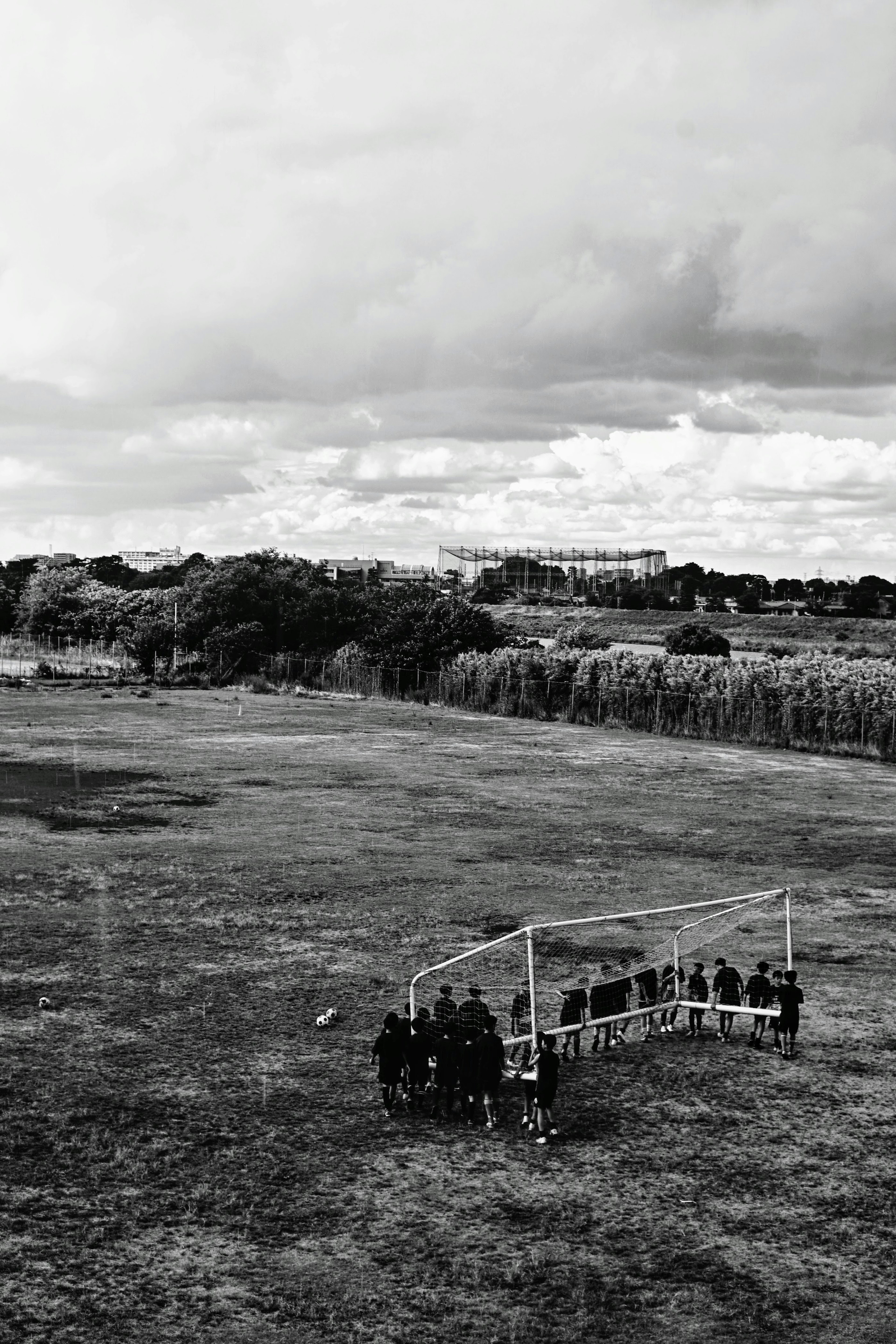 Fußballtor mit Spielern, die auf einem Feld unter einem bewölkten Himmel trainieren