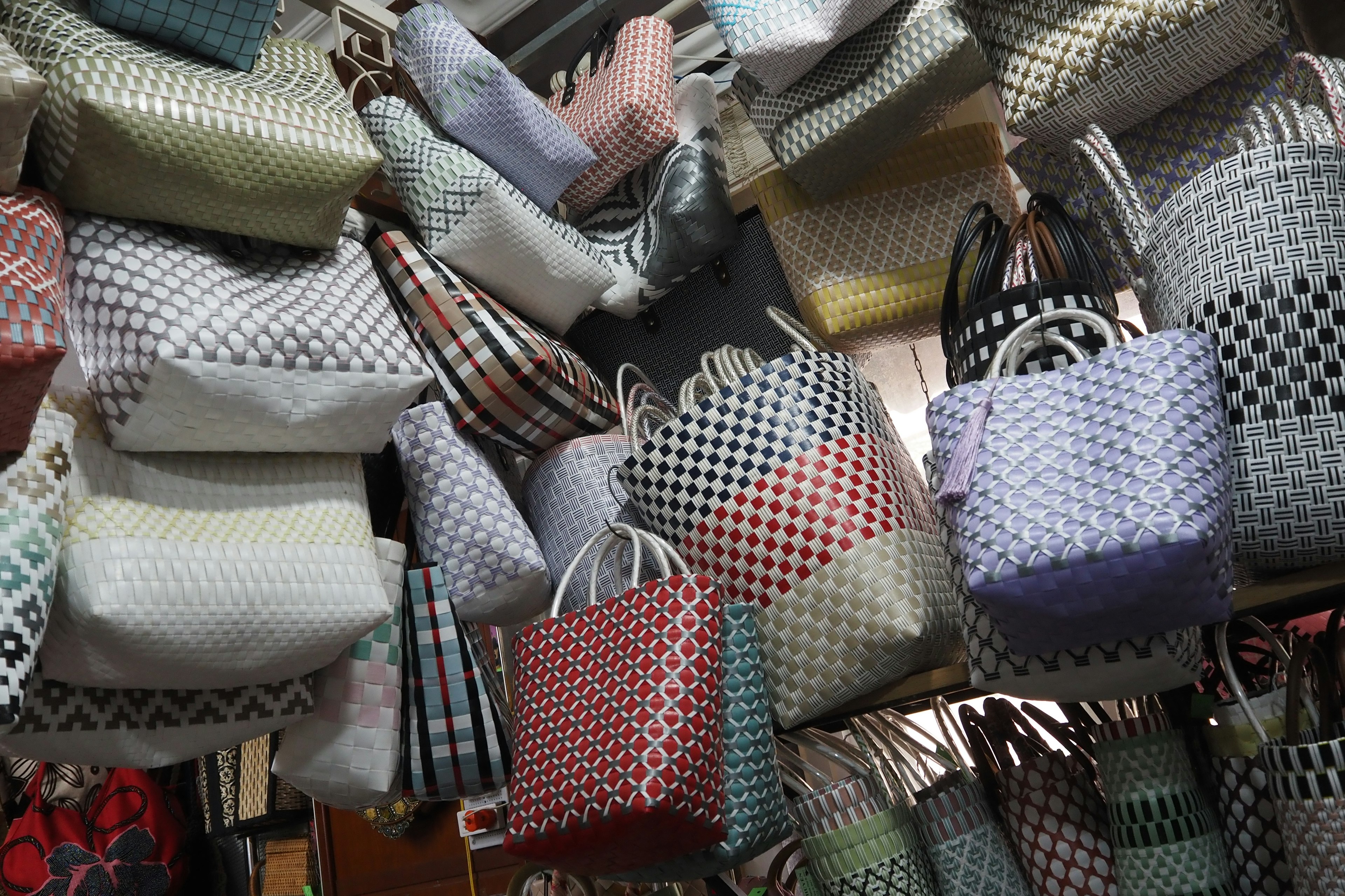 Bolsas tejidas coloridas expuestas en un mercado