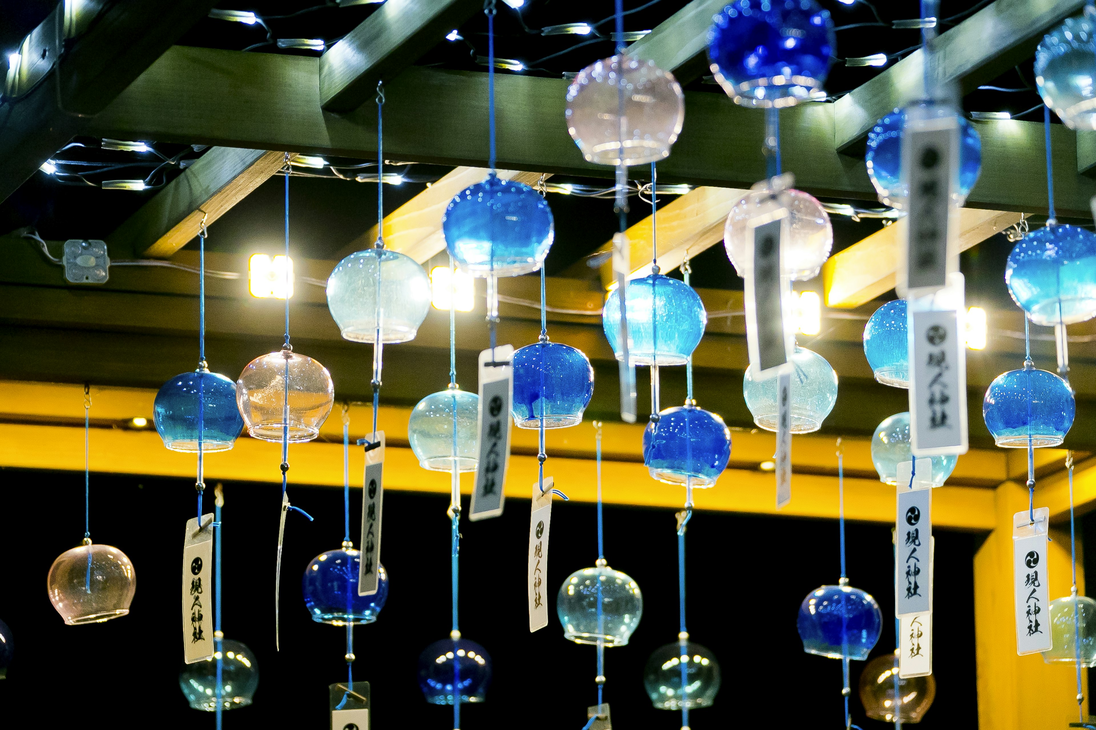 Colorful wind chimes hanging under a roof with lights