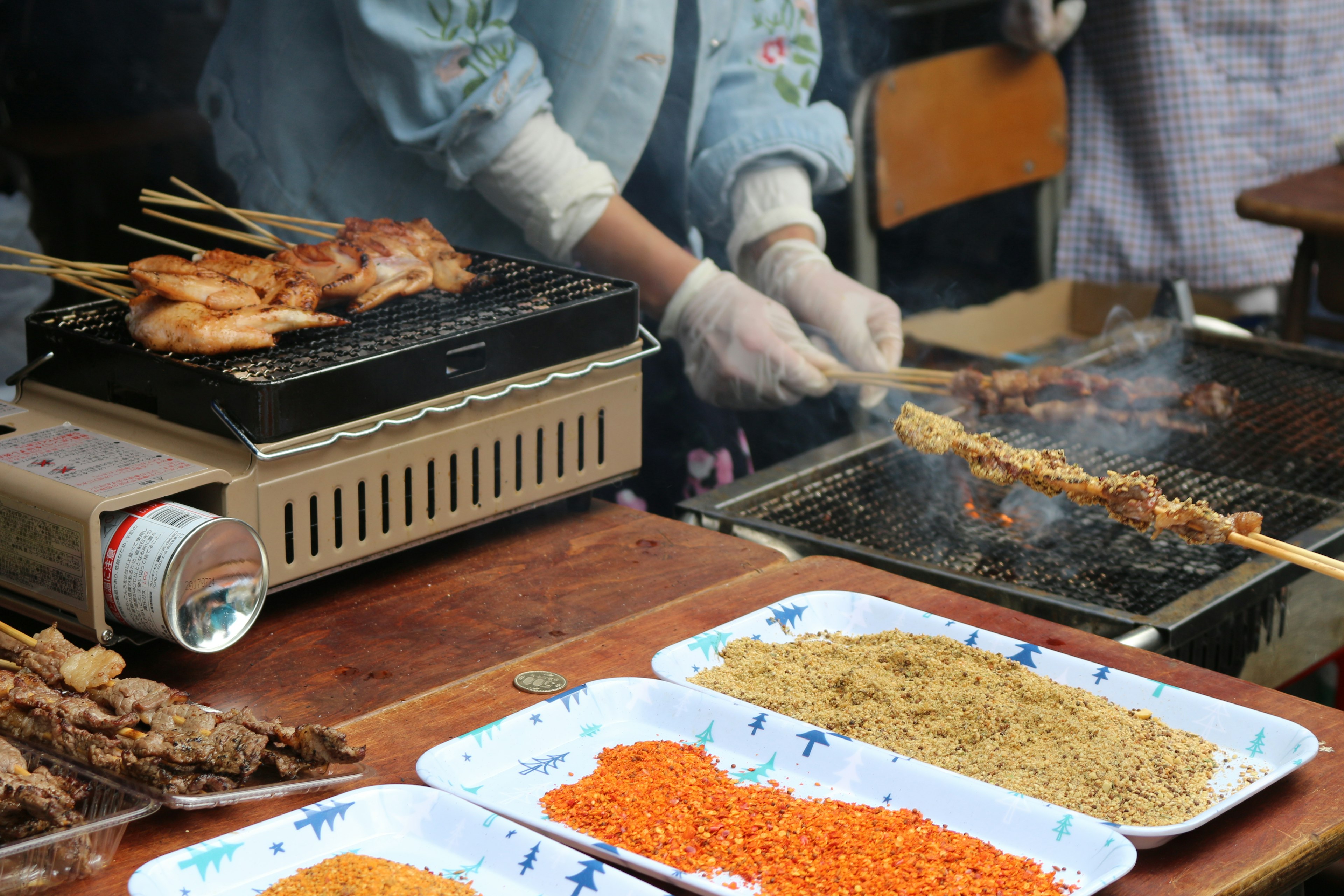 Scene of a street vendor grilling skewered meat with spices displayed