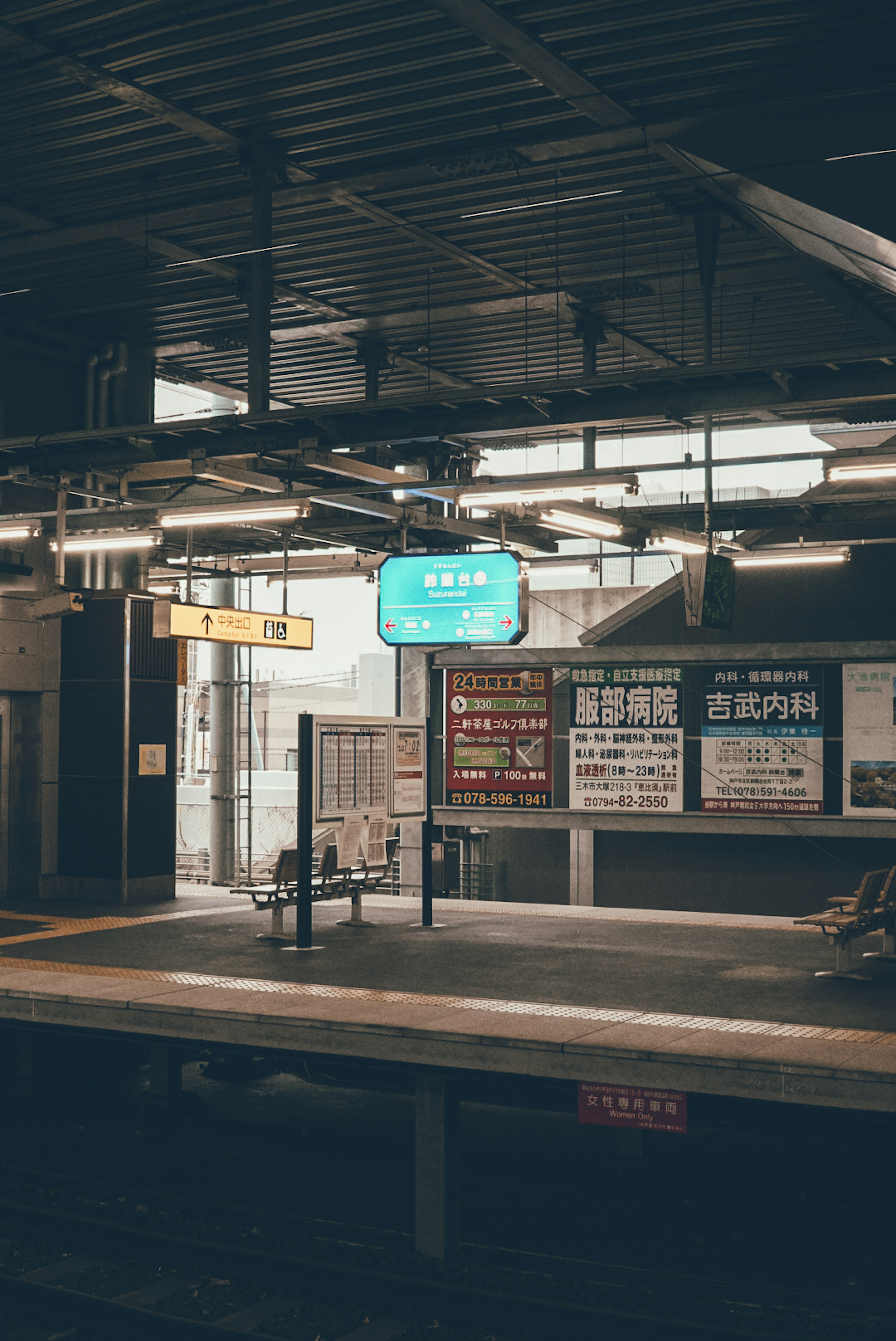 Blick auf die Plattform eines Bahnhofs mit hellen Schildern und verschiedenen Plakaten