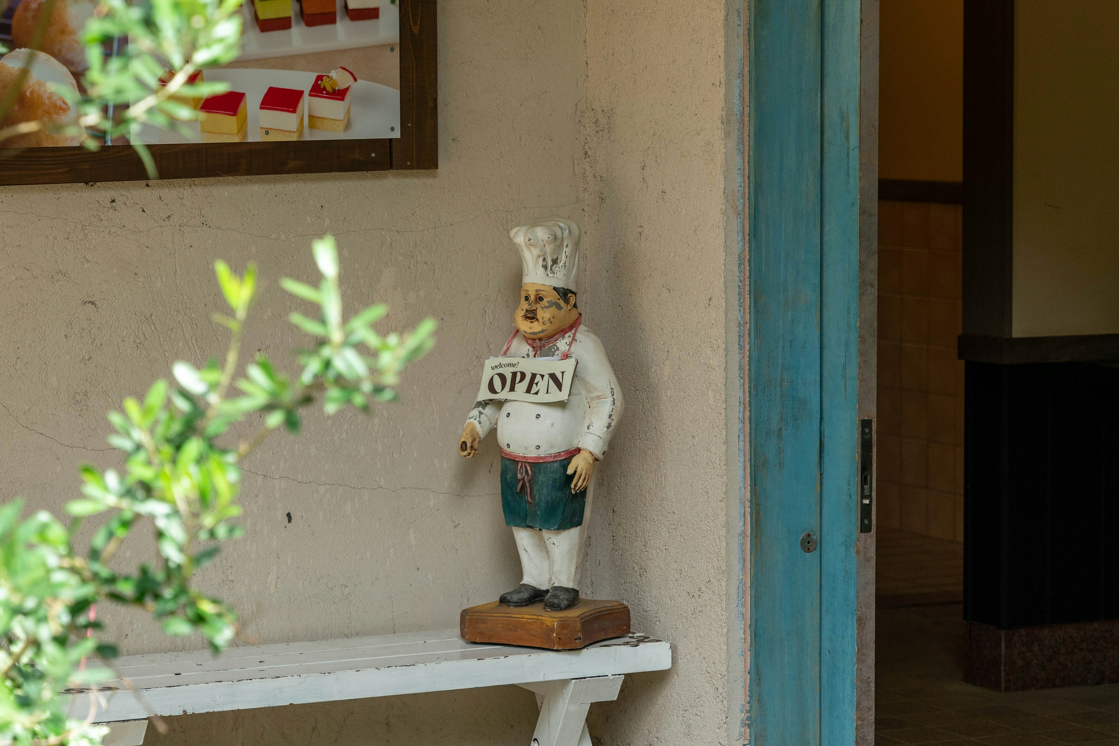 Una figura de chef sosteniendo un letrero de abierto se encuentra en la entrada