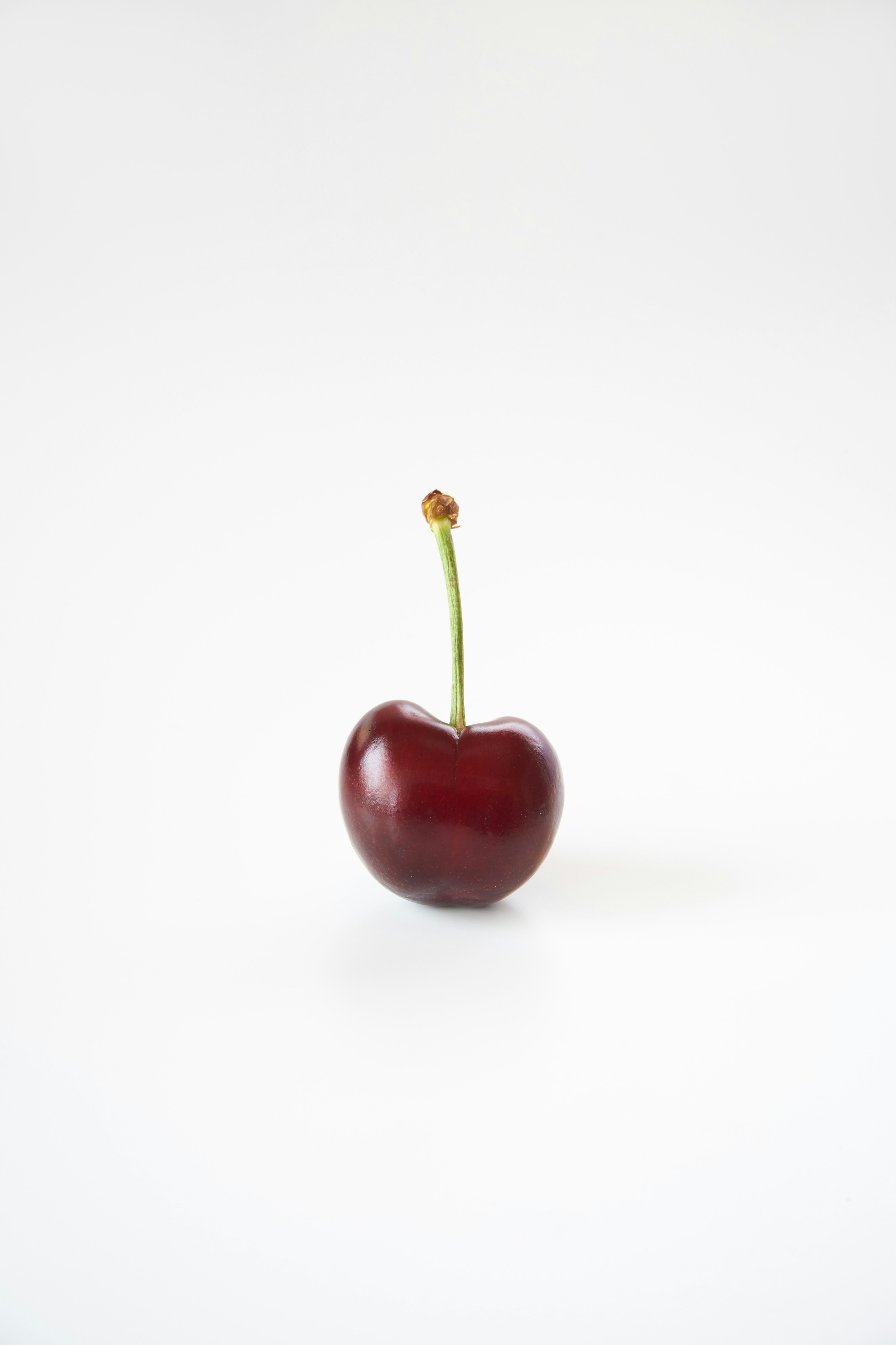 A red cherry standing on a white background