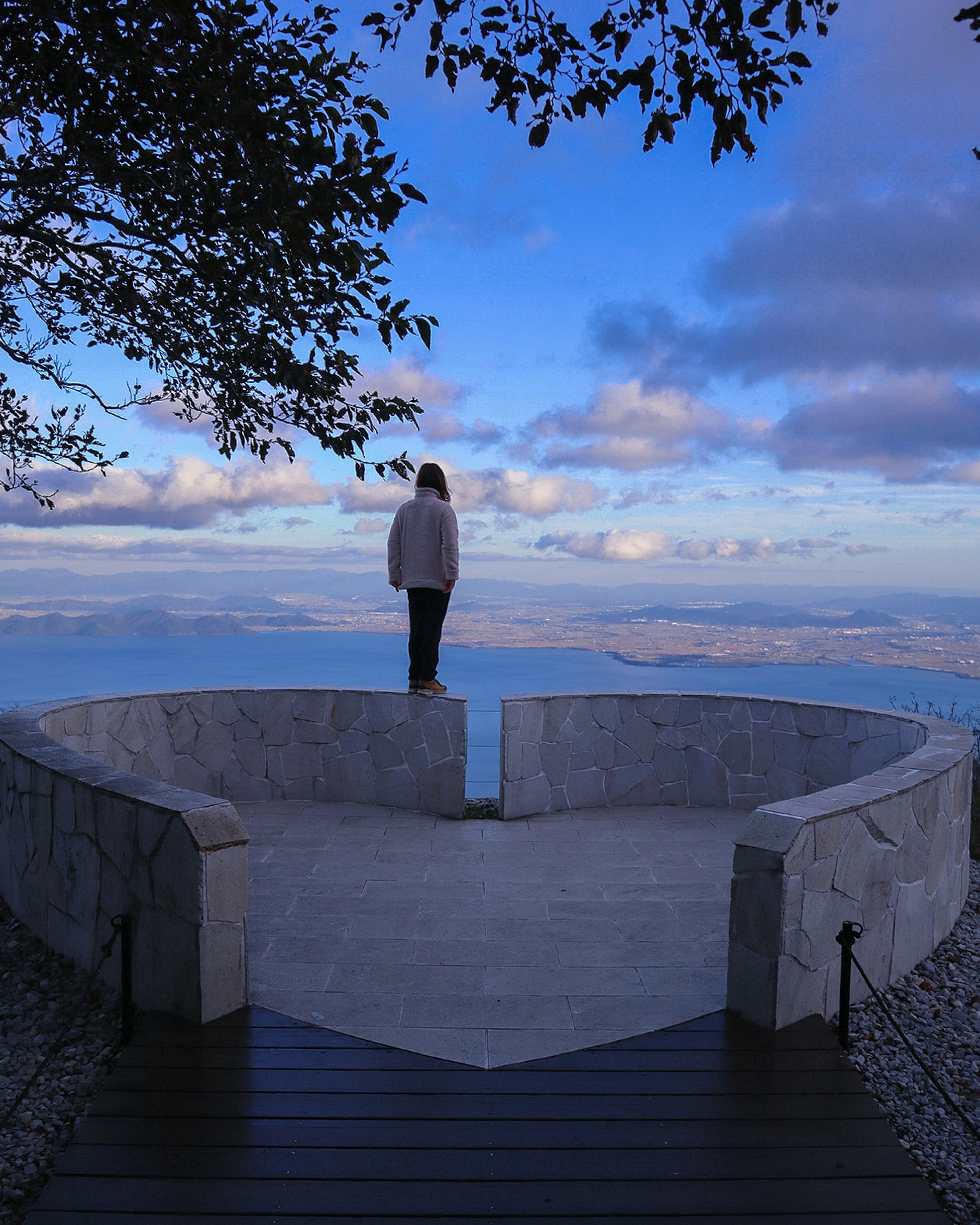 A woman standing on a heart-shaped viewpoint with a scenic background