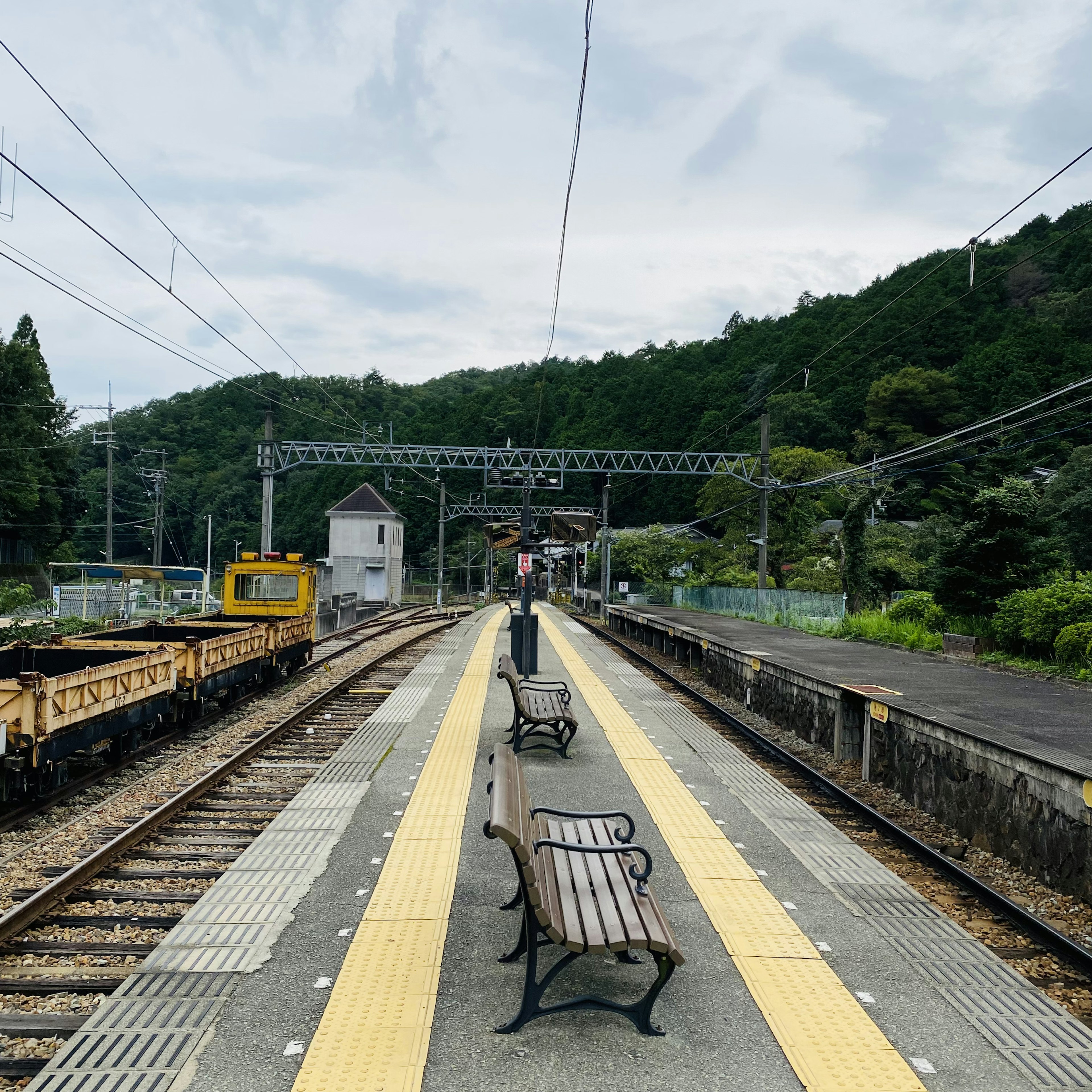 Quiet train station platform with benches and mountain backdrop