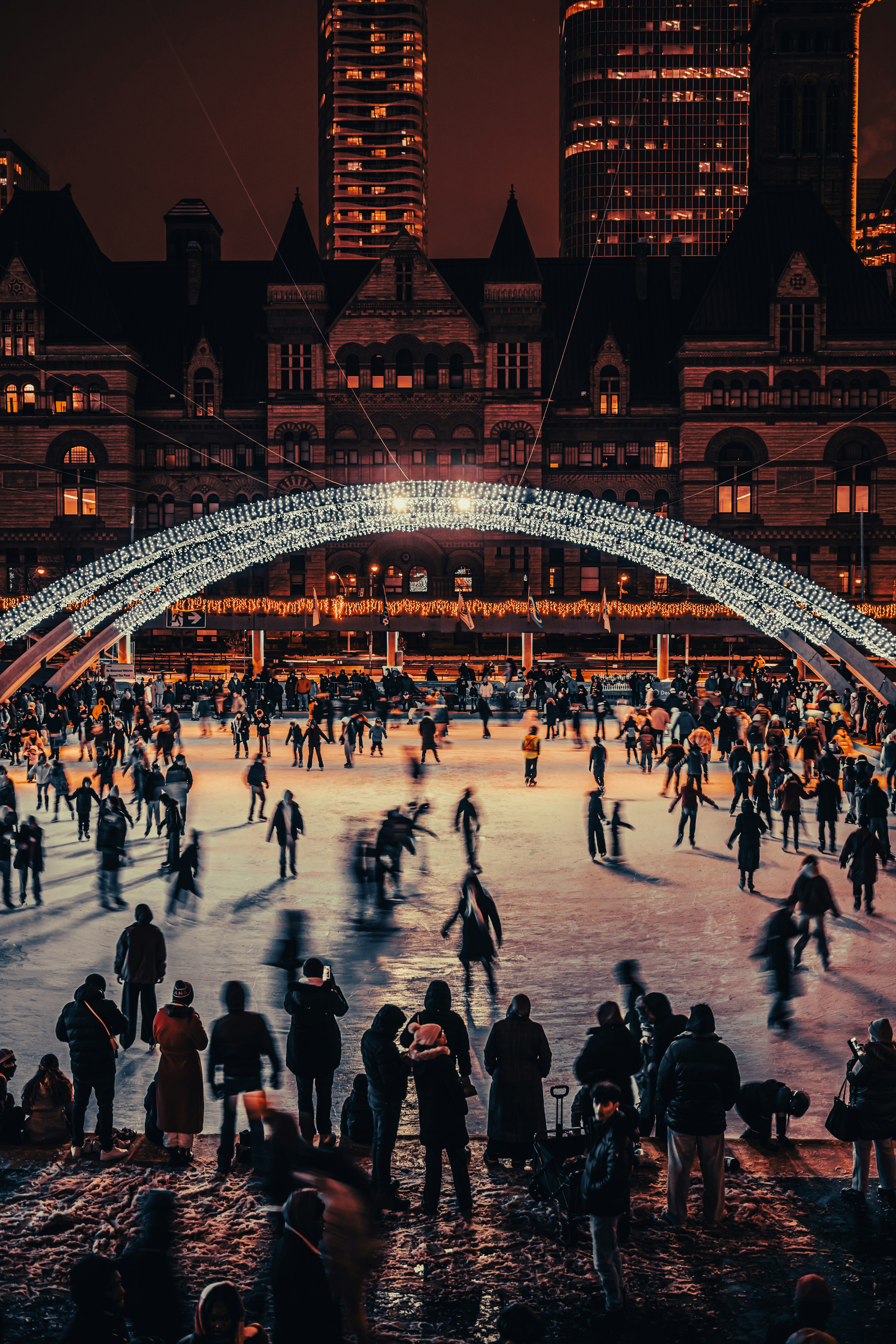 People enjoying a night ice skating rink with a beautiful arch bridge