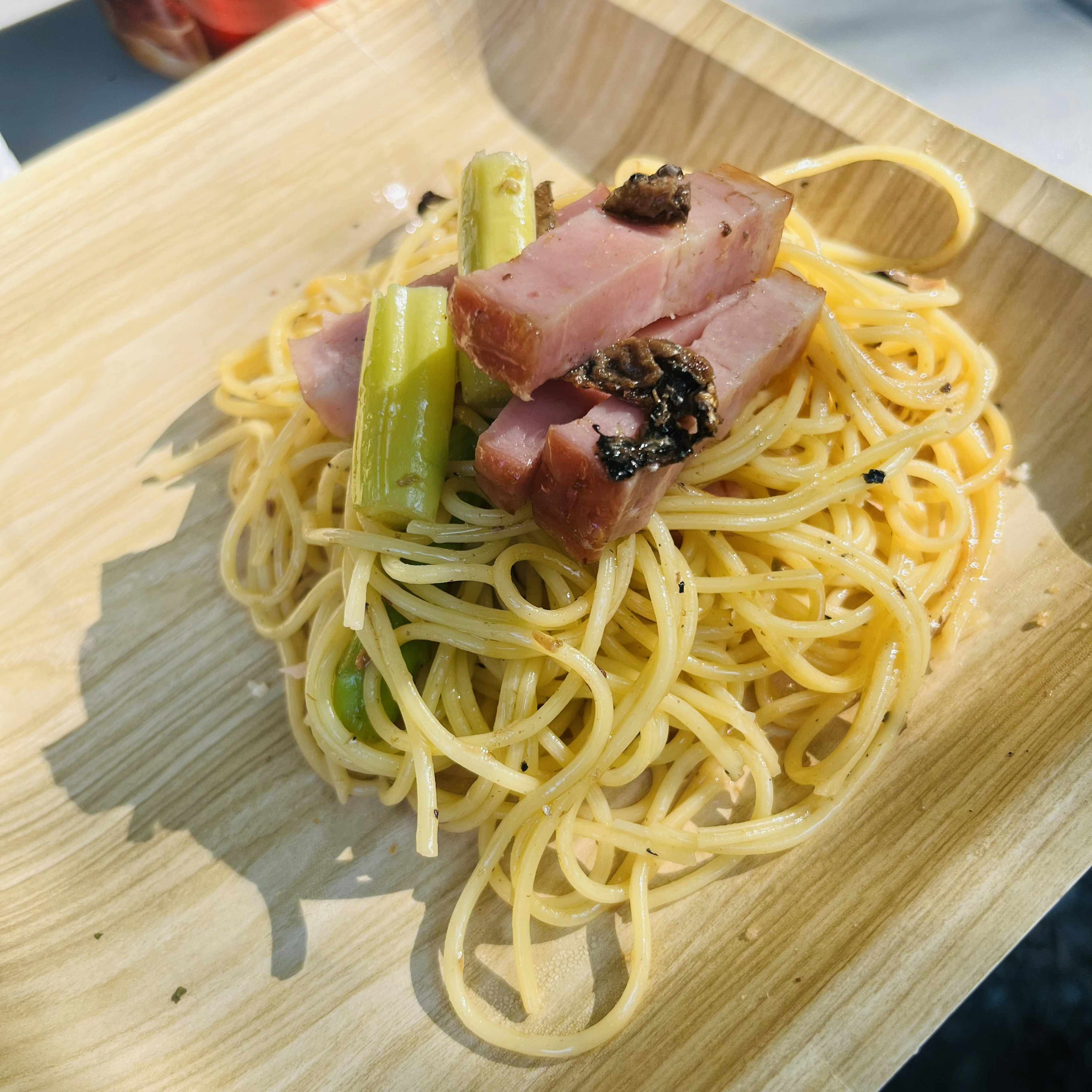 A plate of spaghetti topped with celery and slices of ham