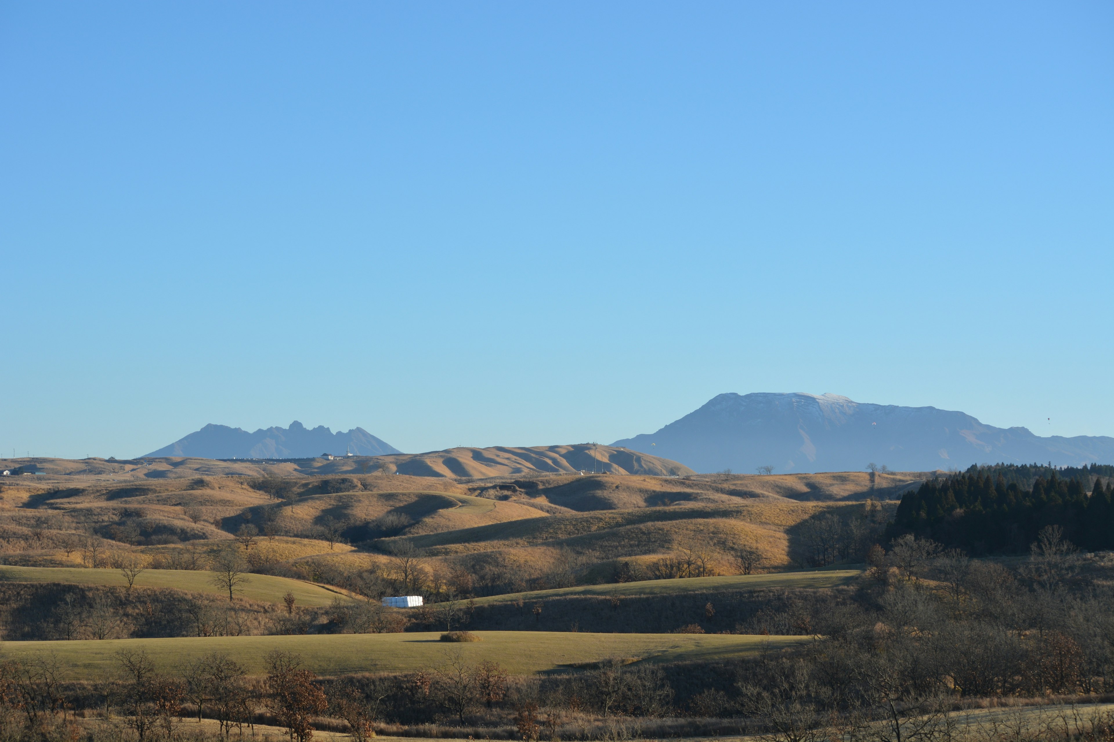 Colline ondulate sotto un cielo blu chiaro con montagne lontane