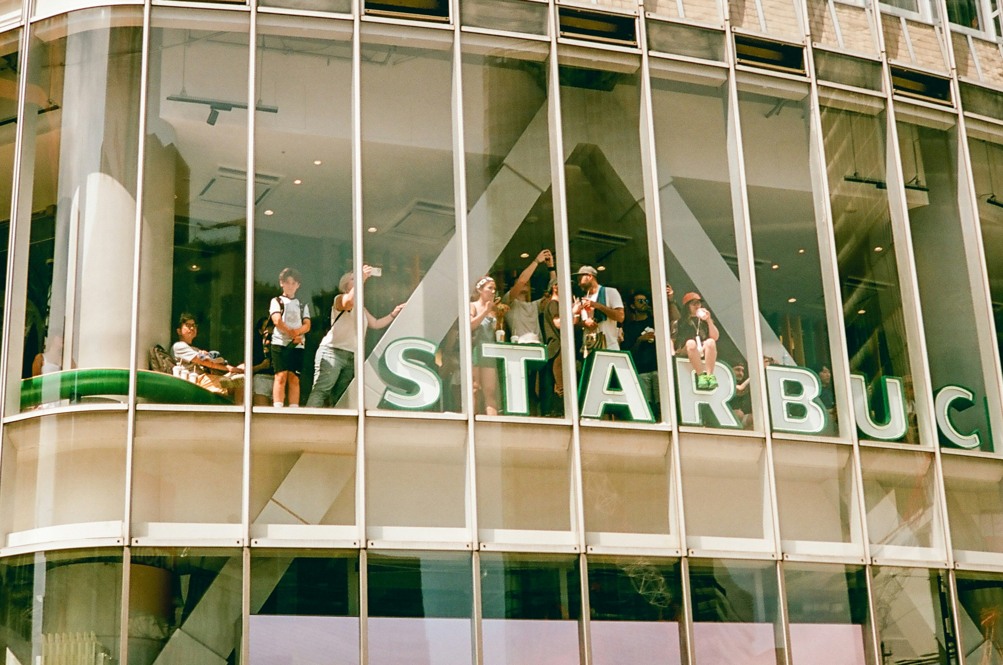 スターバックスのガラス張りの店舗で楽しむ人々