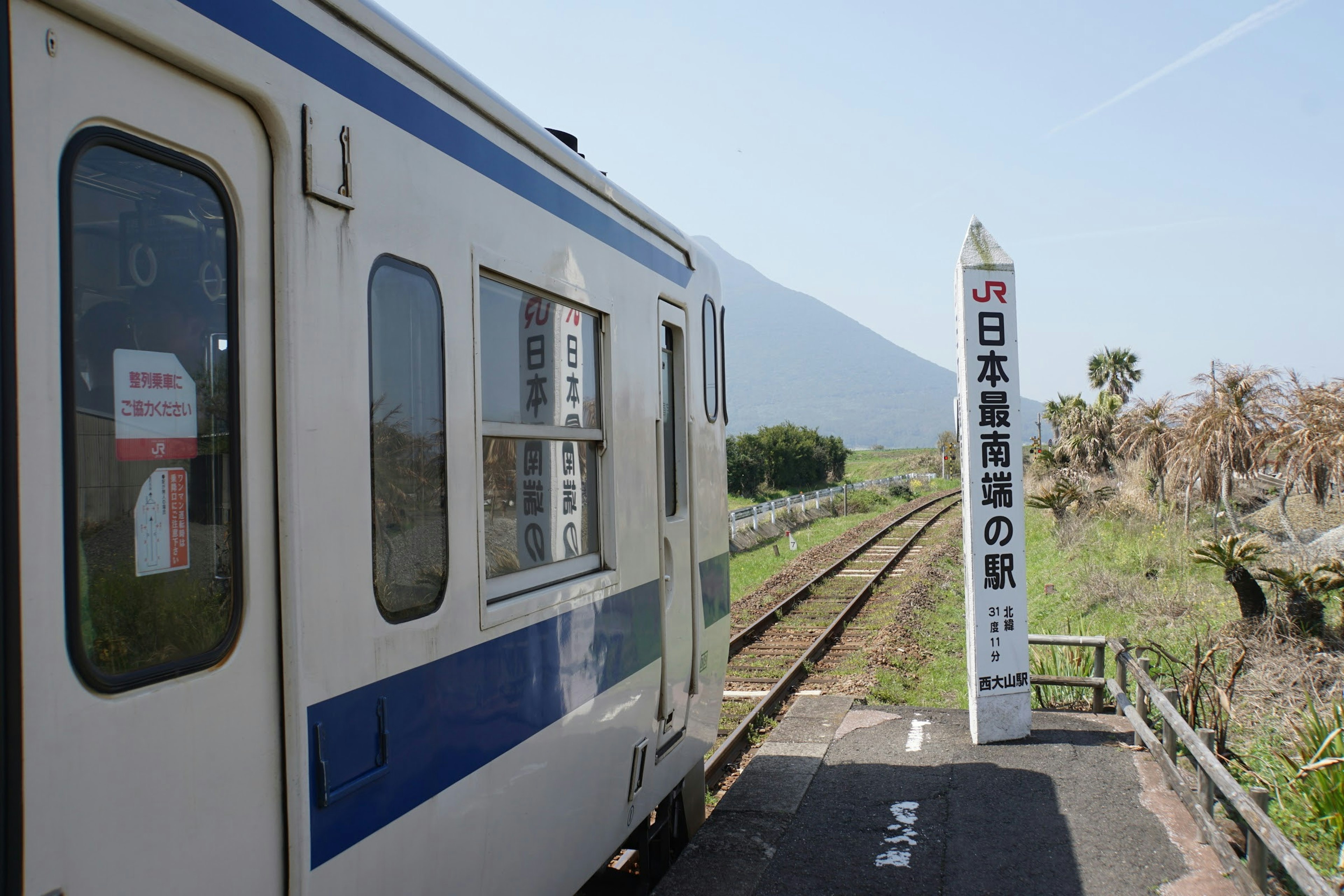 日本の田舎の駅に停車中の列車の側面と駅の標識