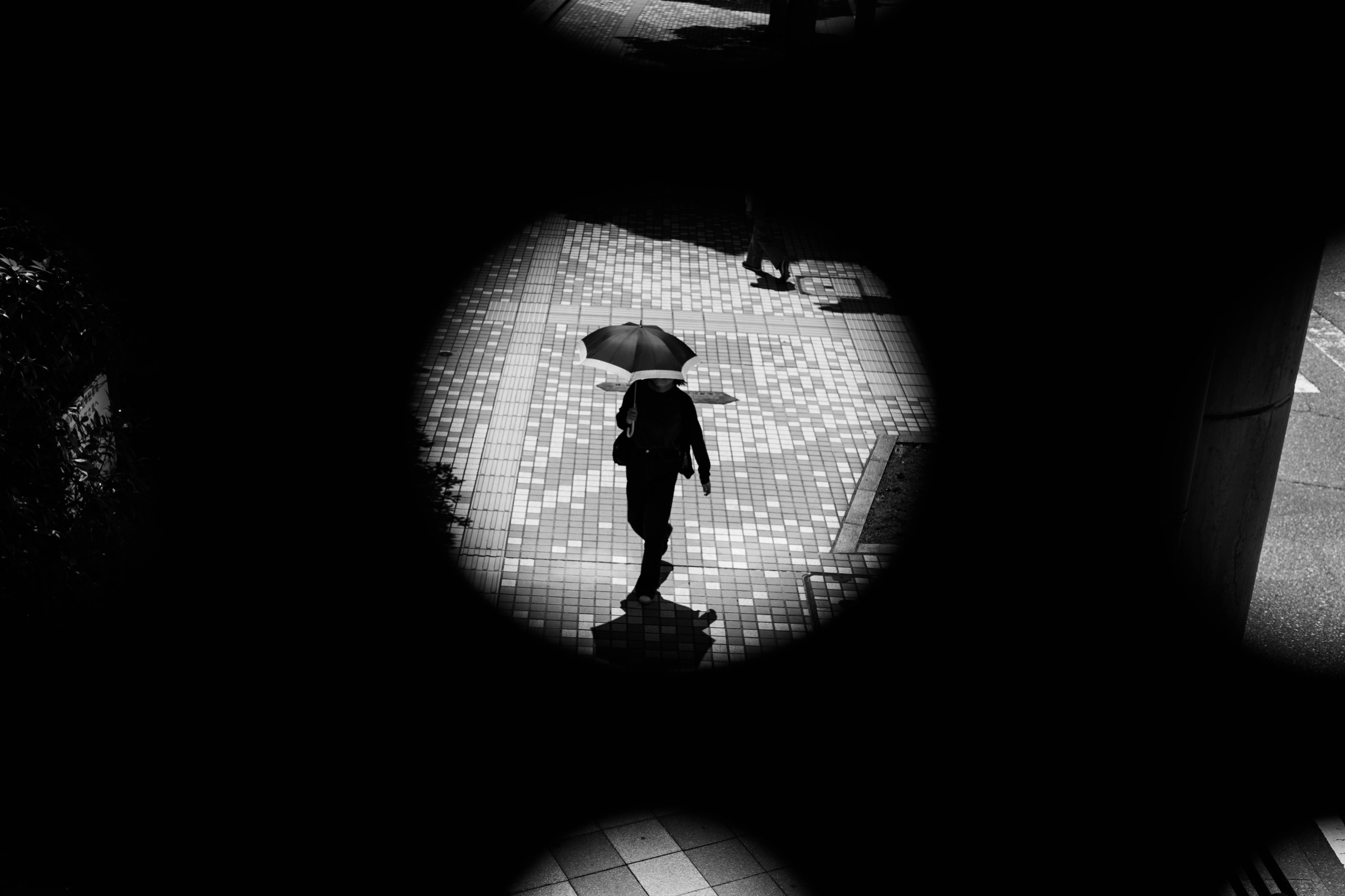 A silhouette of a person holding an umbrella walking on a street