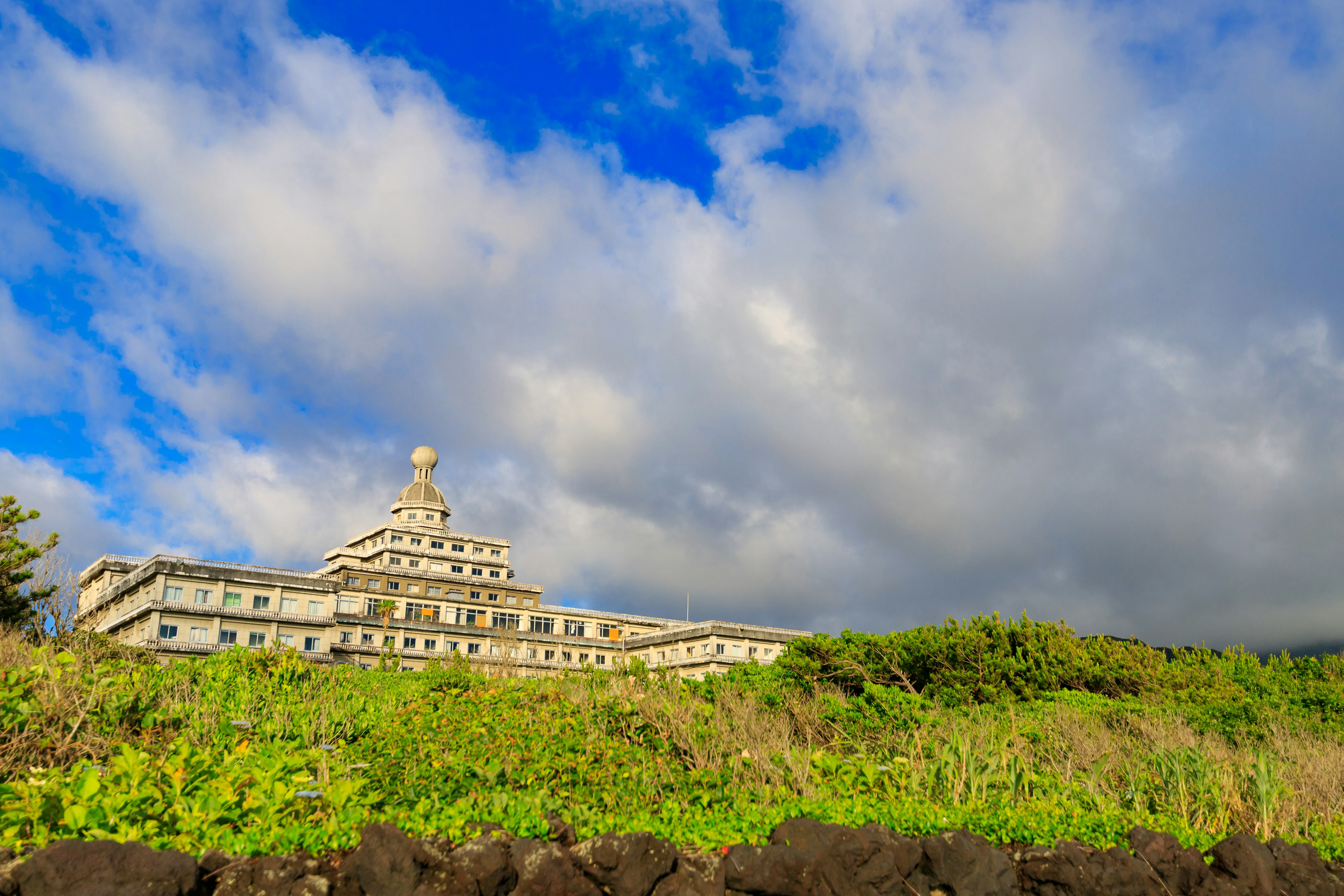 A beautiful building under a blue sky with clouds and green grass